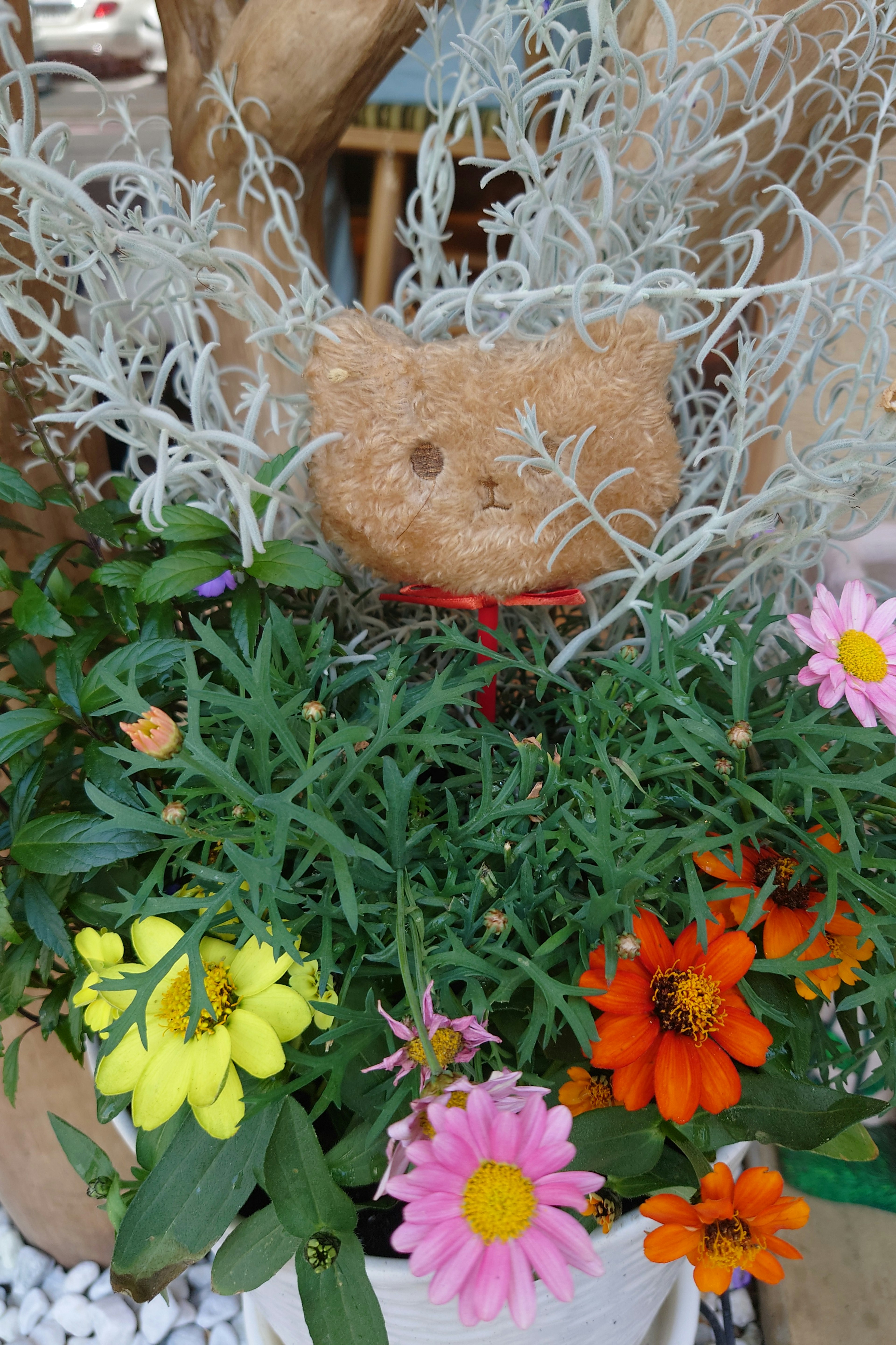 Scultura di orso carina circondata da fiori colorati e vegetazione