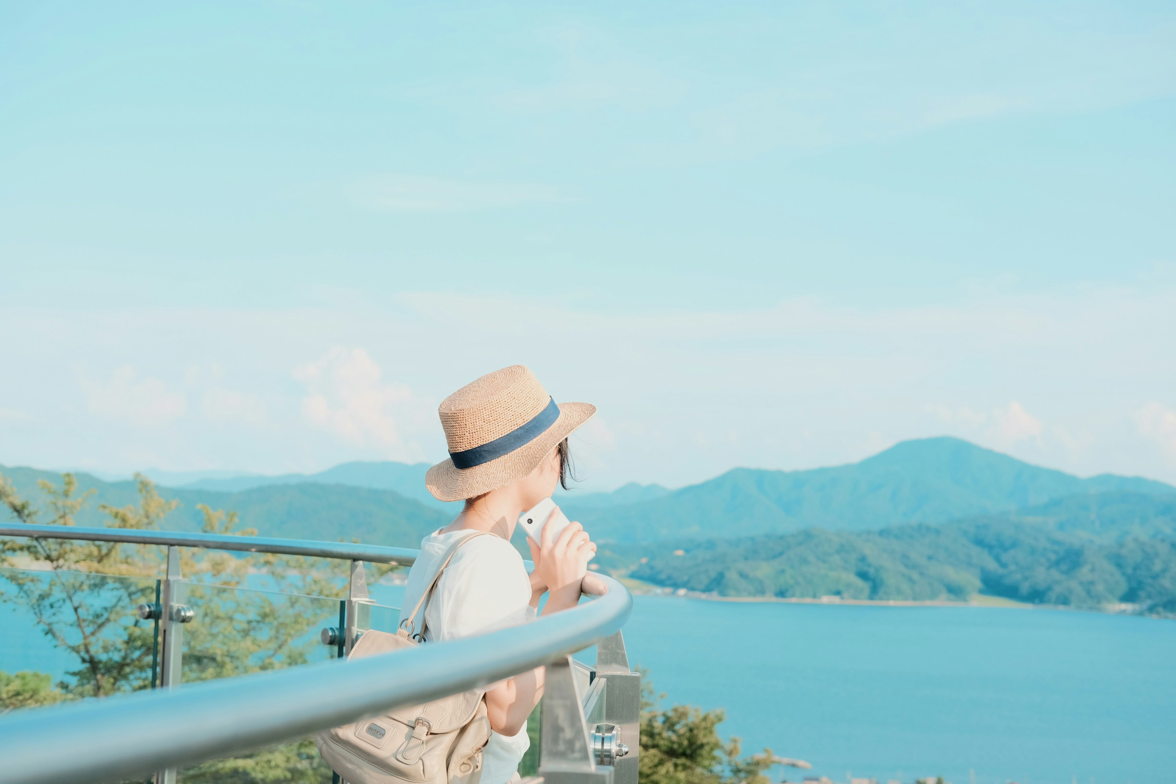 Woman wearing a hat overlooking a scenic view of the sea and mountains