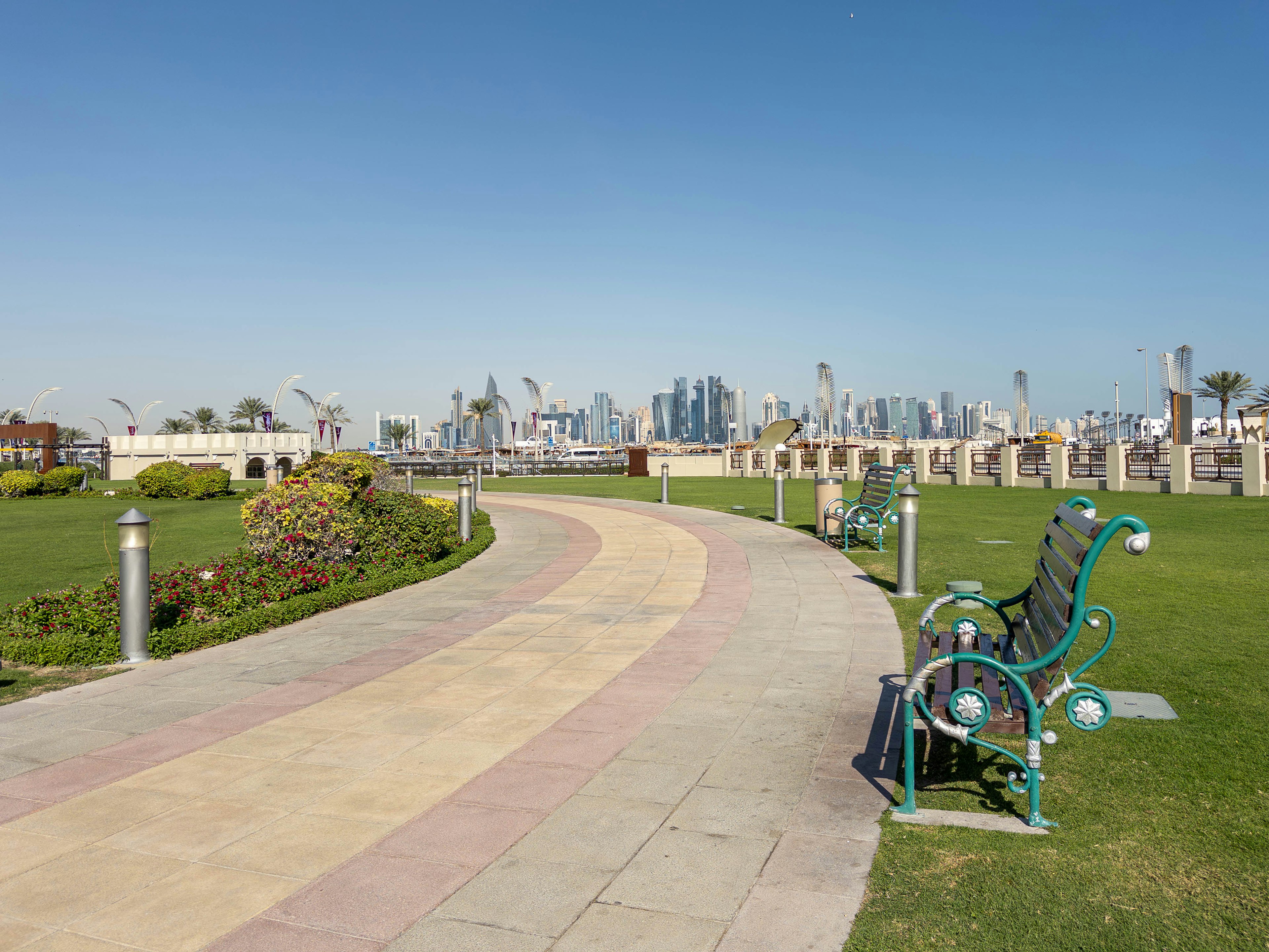 Park pathway with benches and city skyline in the background