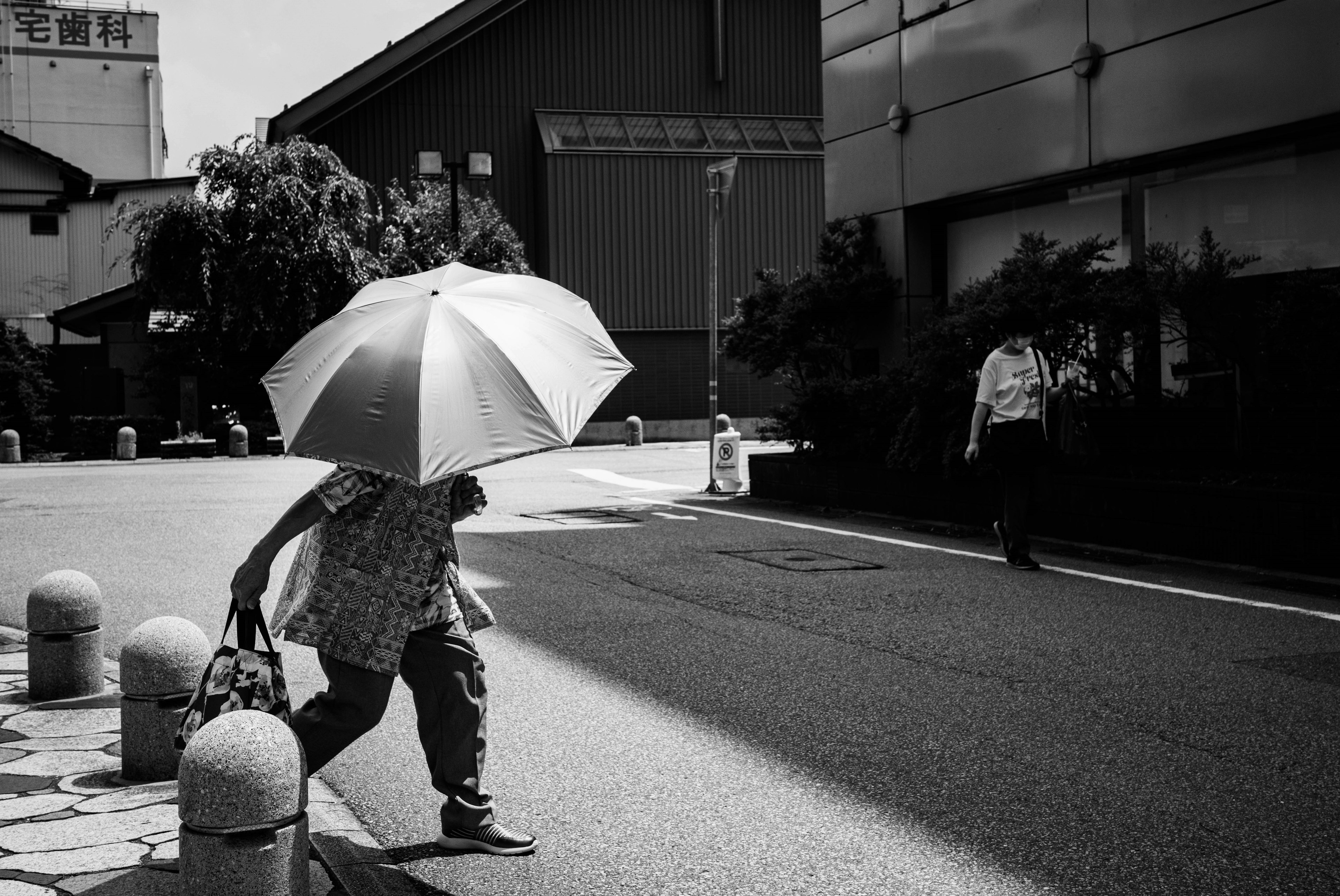 Person walking with an umbrella in a black and white urban setting