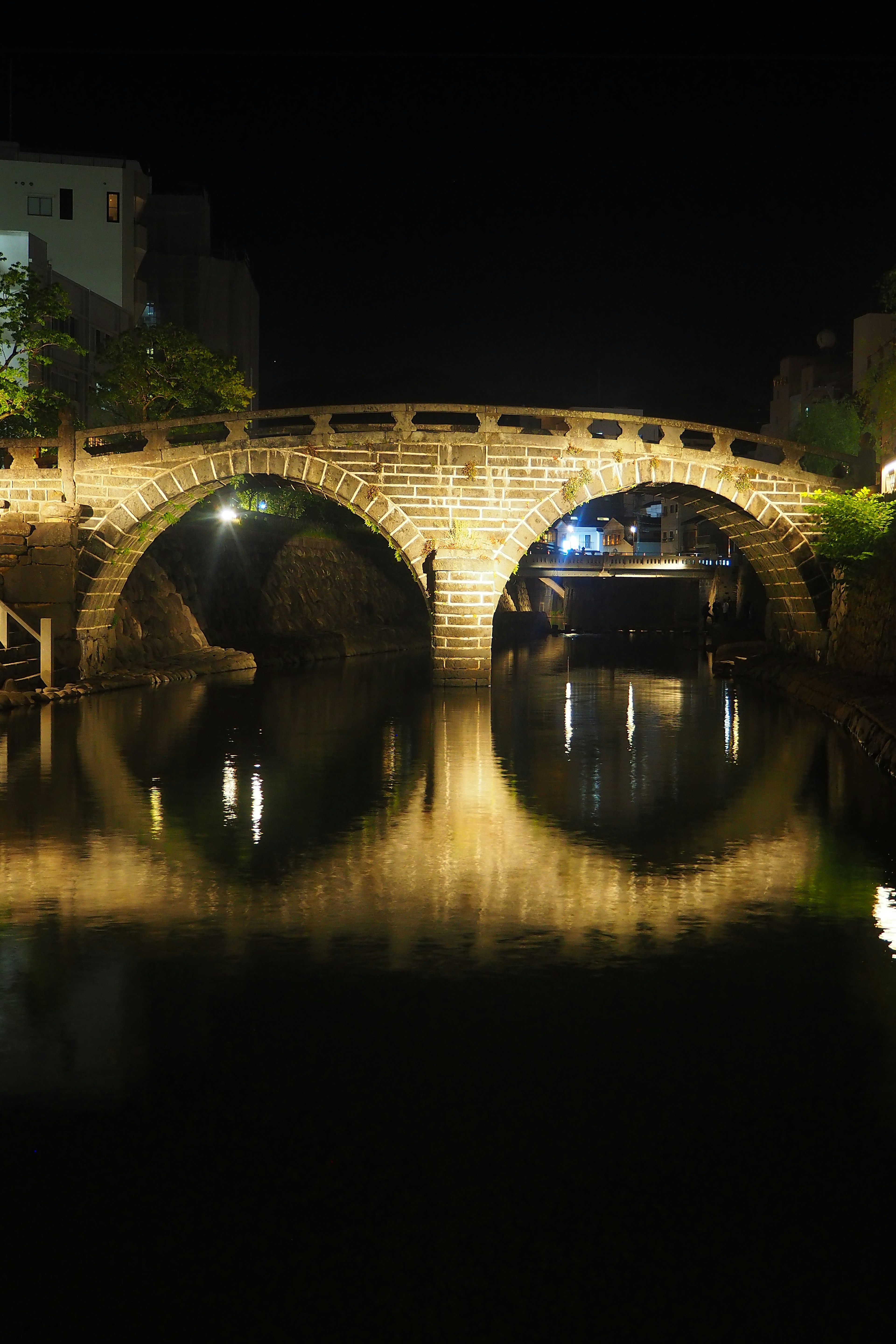 Hermosa escena nocturna de un puente de piedra reflejado en el agua