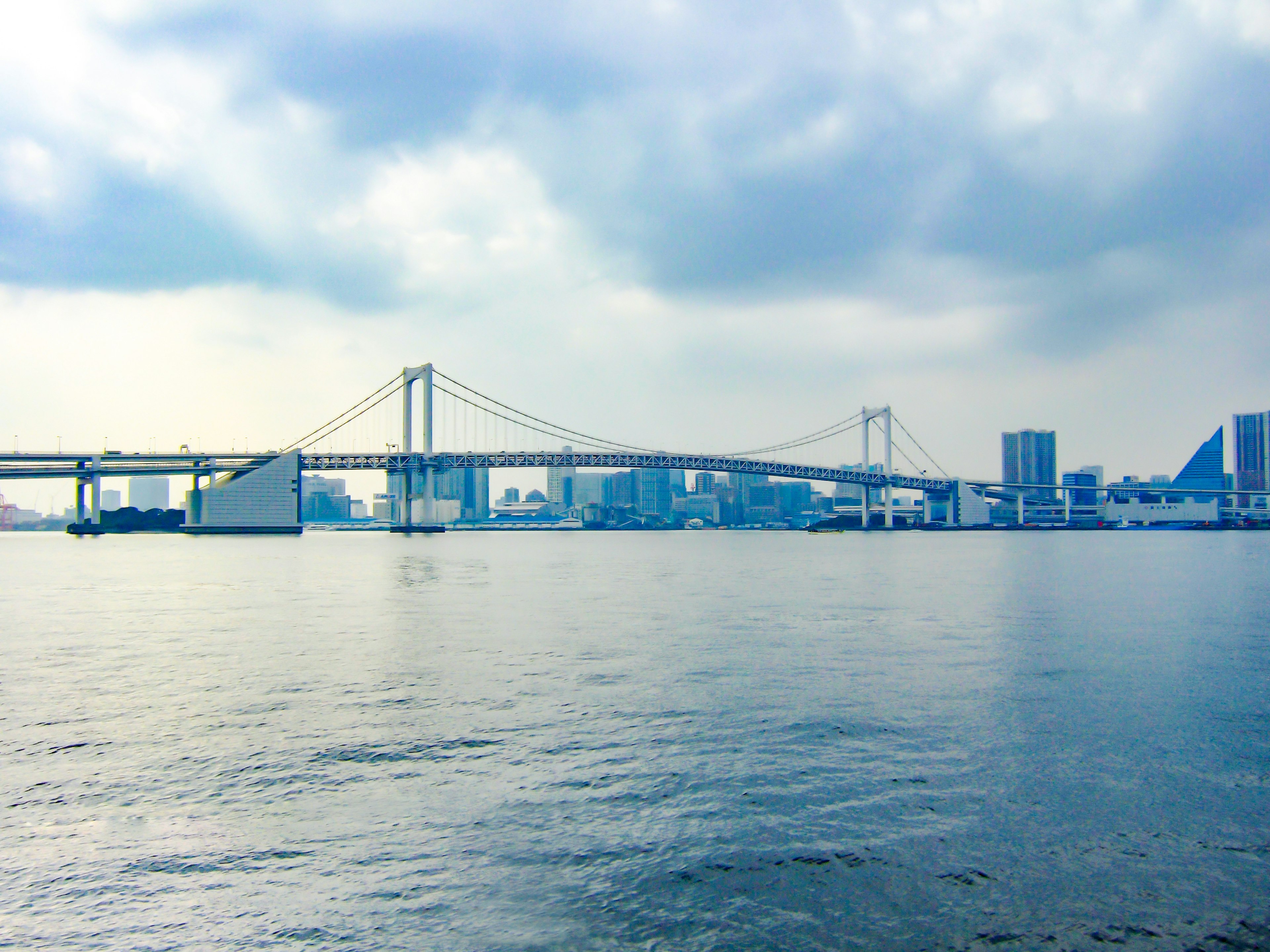 Pemandangan Jembatan Pelangi dengan cakrawala Tokyo di latar belakang di atas air