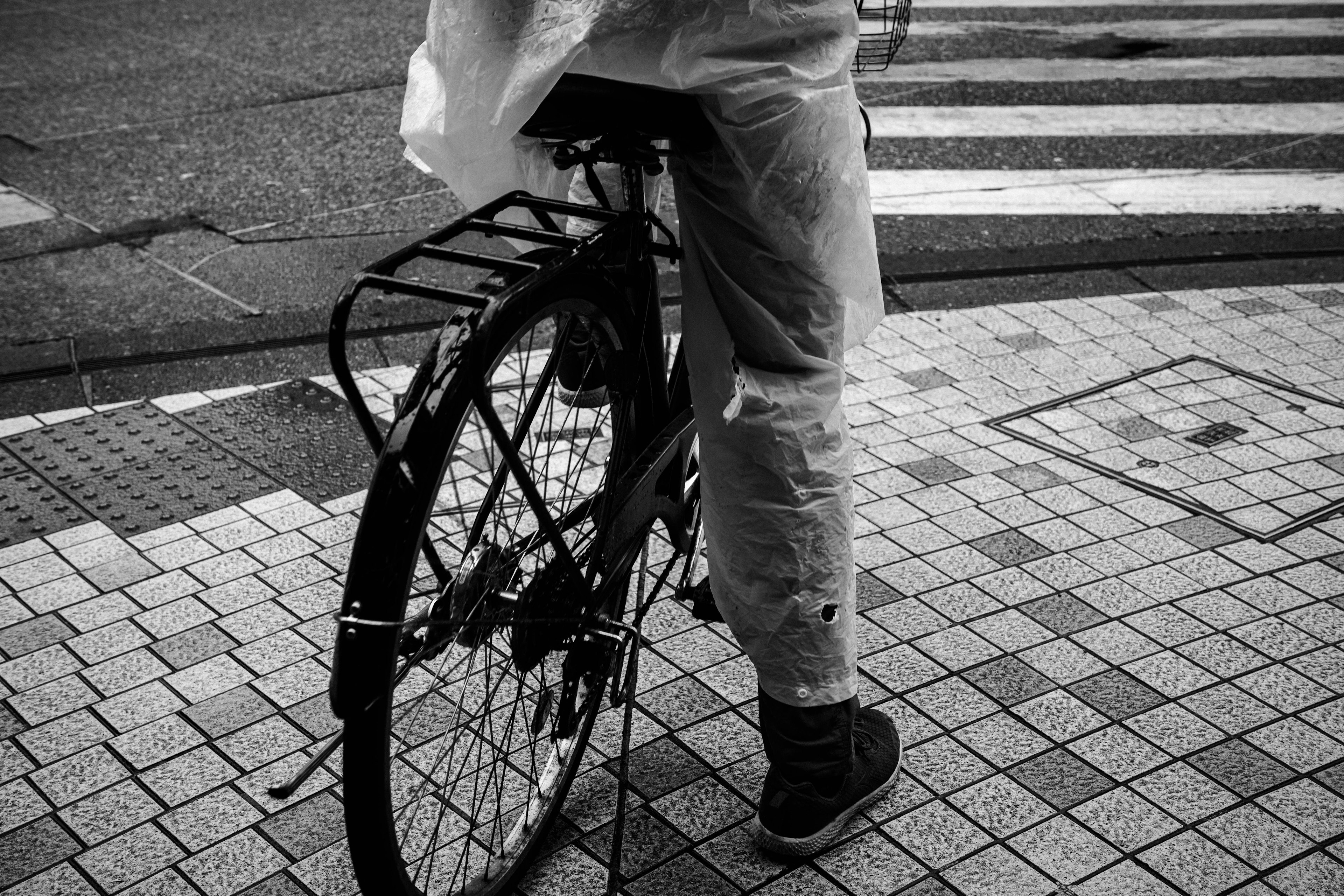 A person standing next to a bicycle on wet pavement with a crosswalk