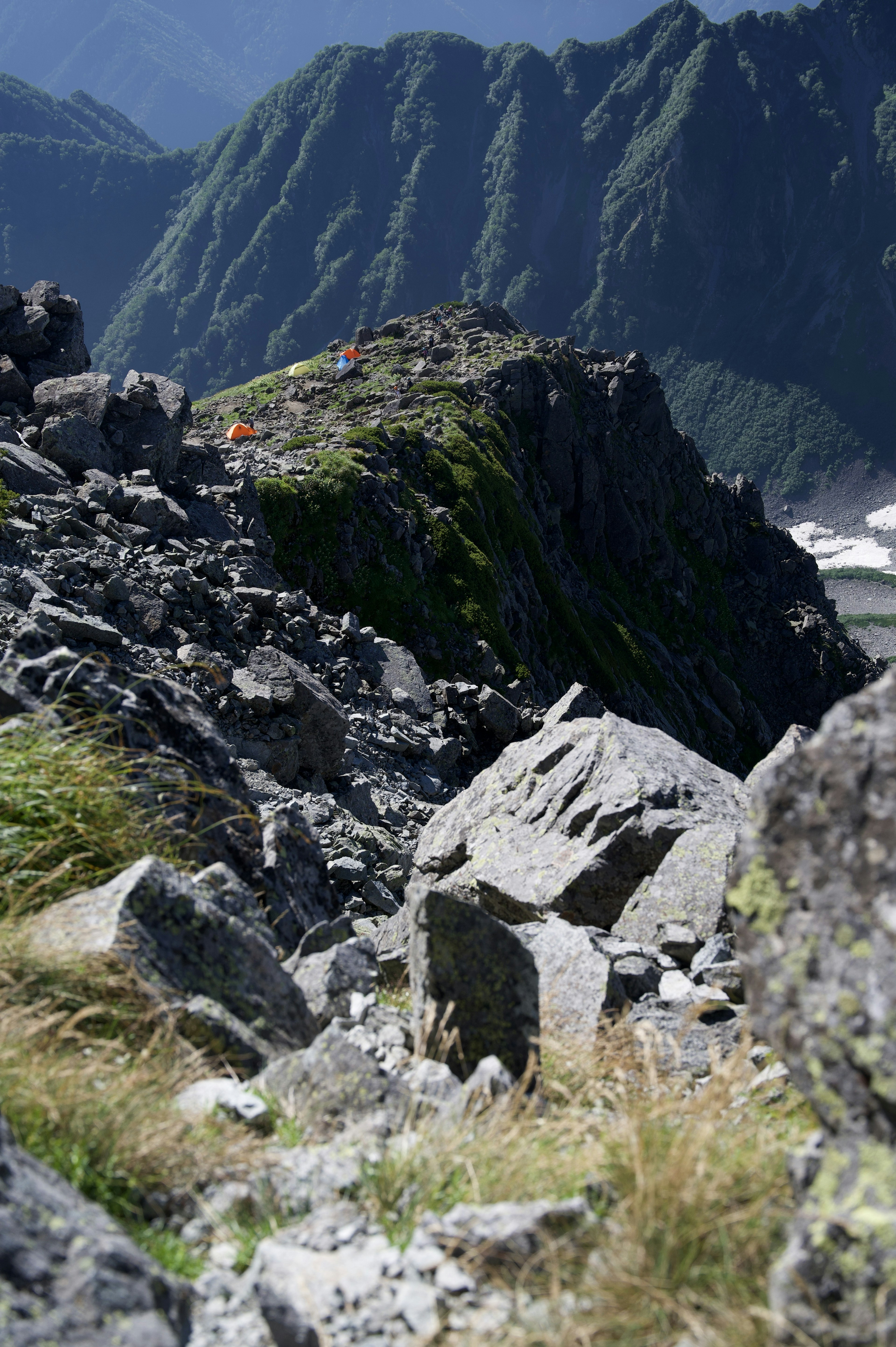 Paysage montagneux rocheux avec une zone herbeuse et un ciel bleu en arrière-plan