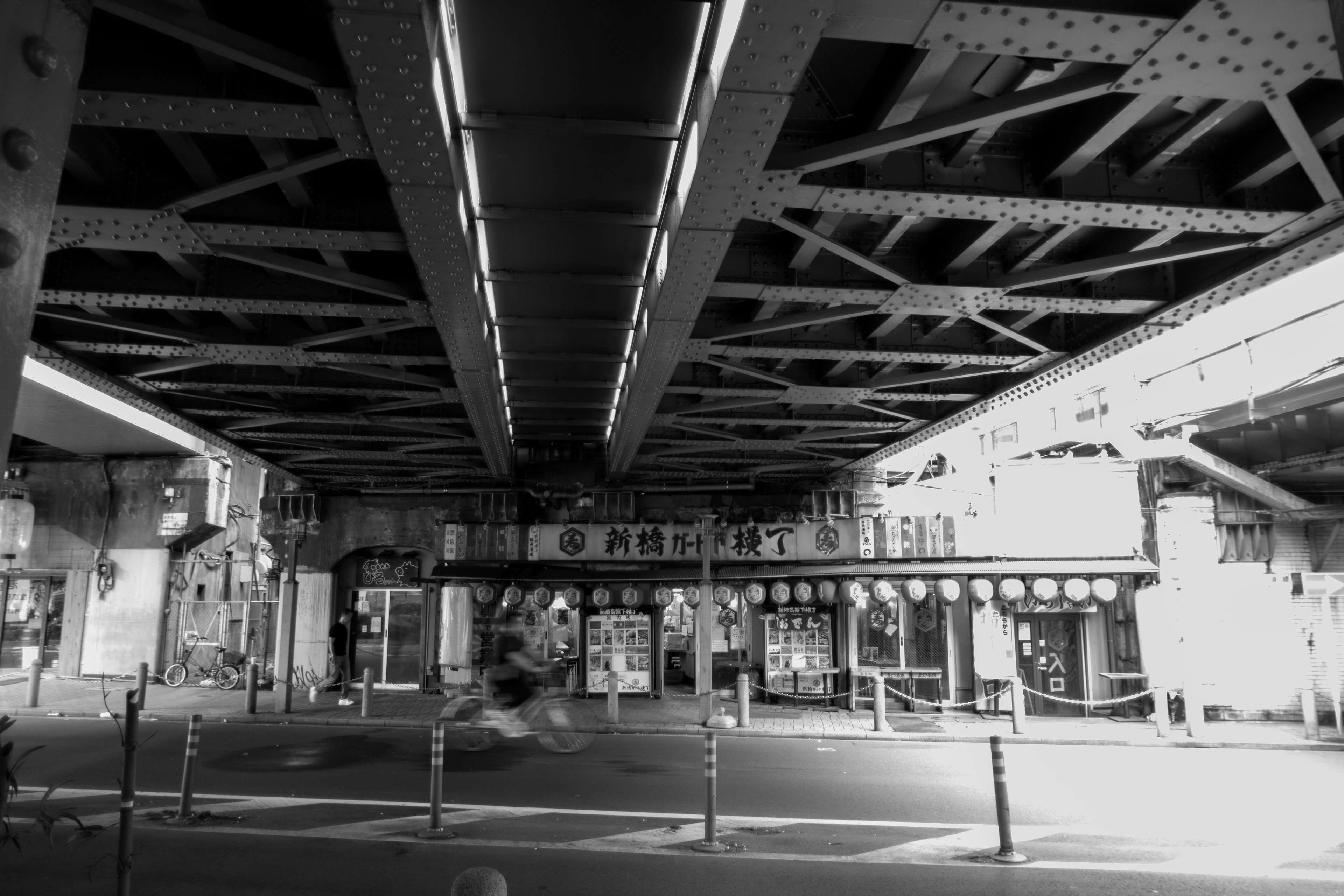 Scène urbaine en noir et blanc avec des structures et des panneaux sous un pont