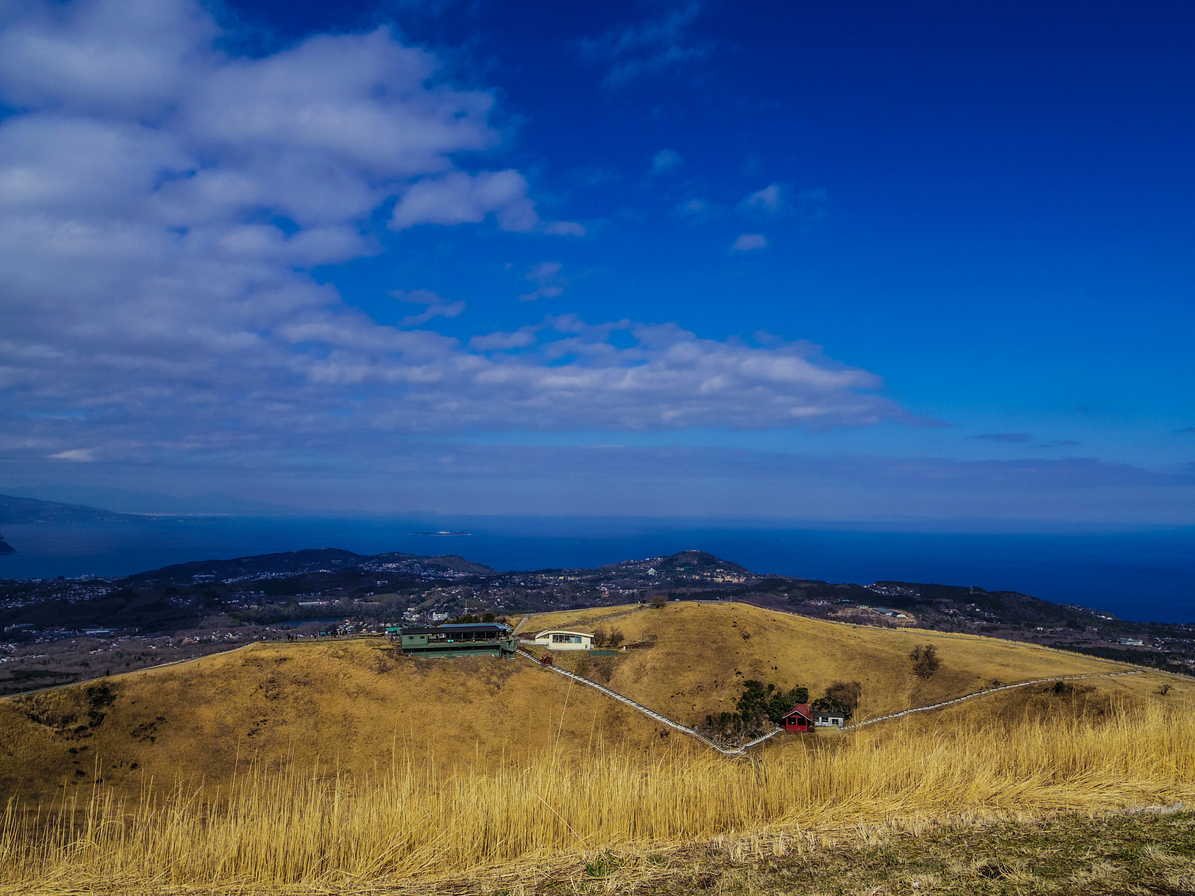 Landscape of rolling hills under a blue sky with clouds ocean visible in the distance