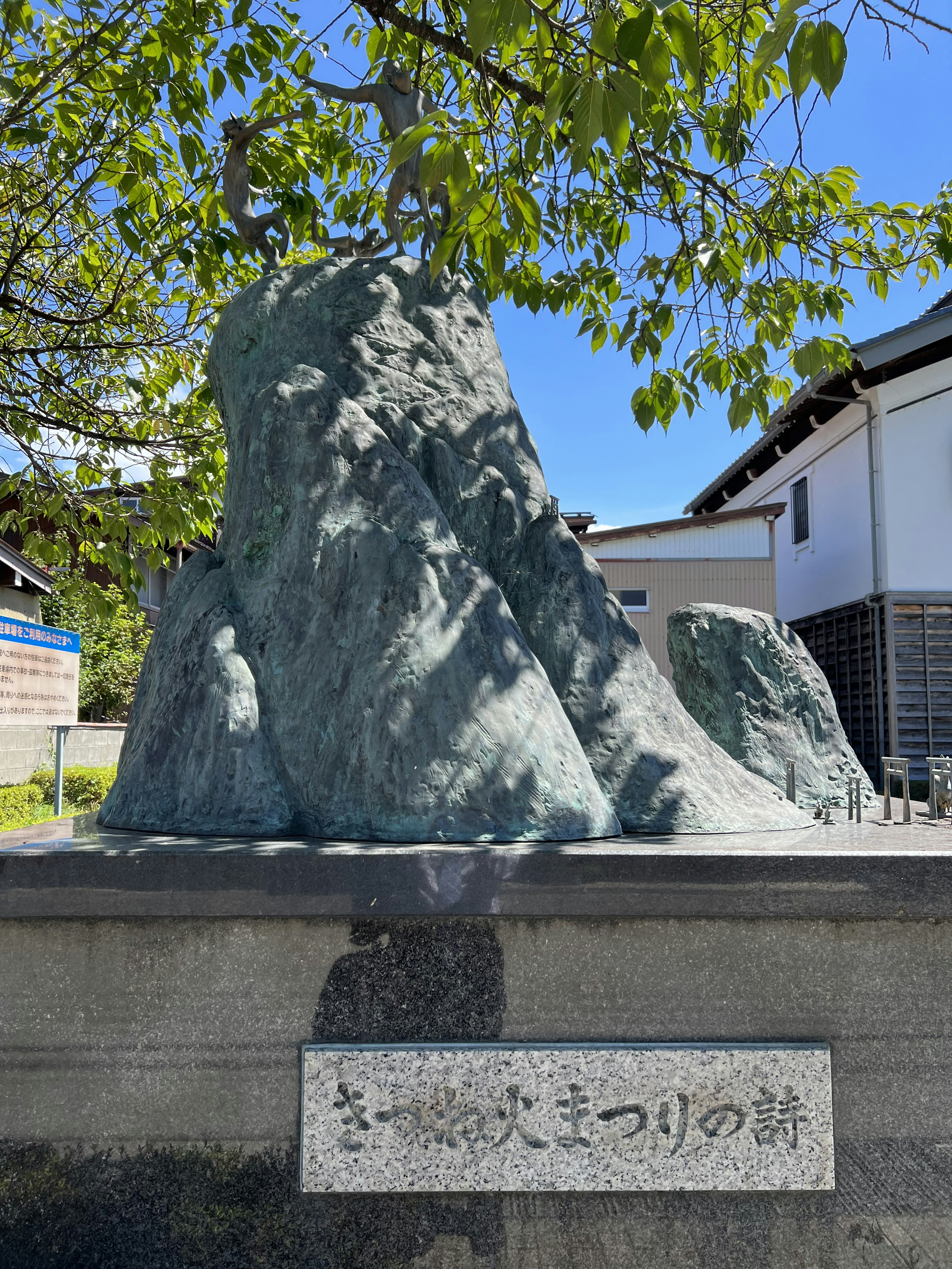 Bronze sculpture under a blue sky with a stone plaque