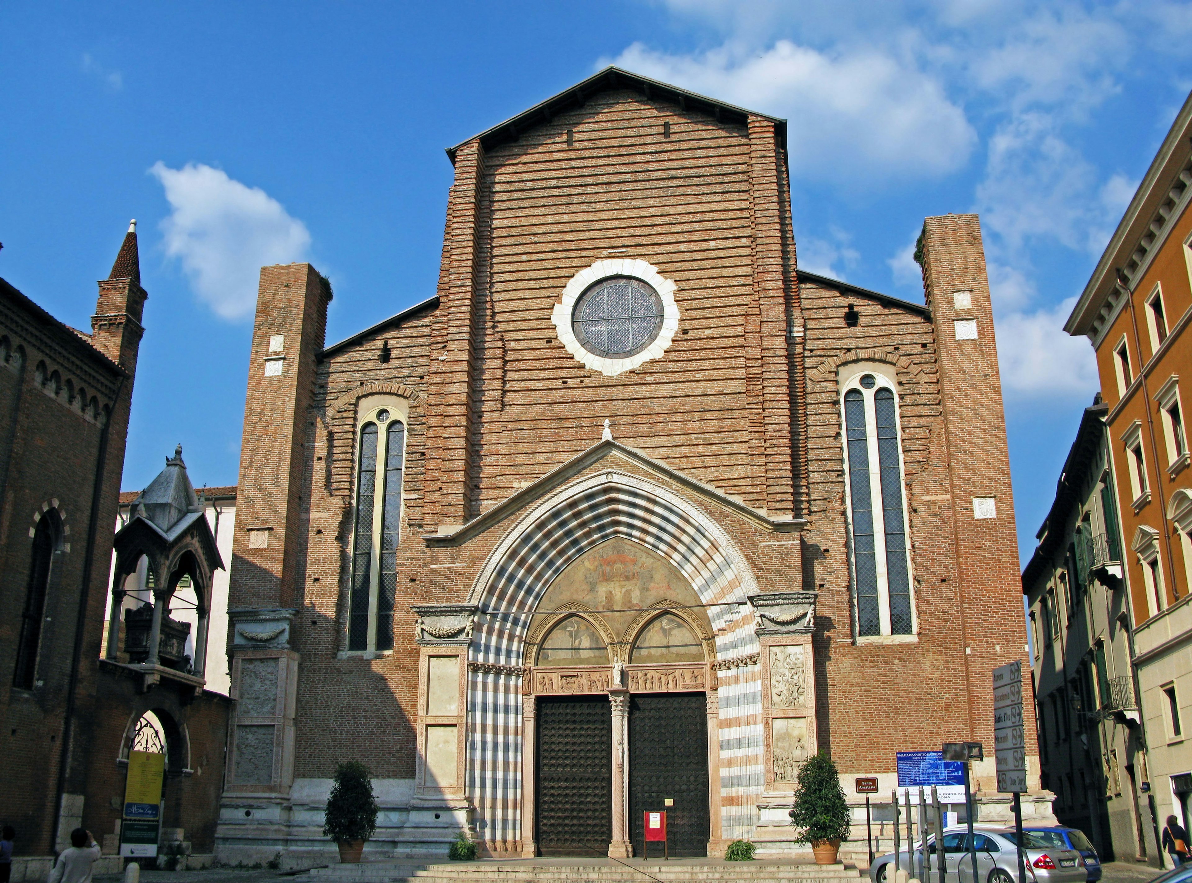 Facade of a church with reddish-brown brick walls circular window and arched entrance