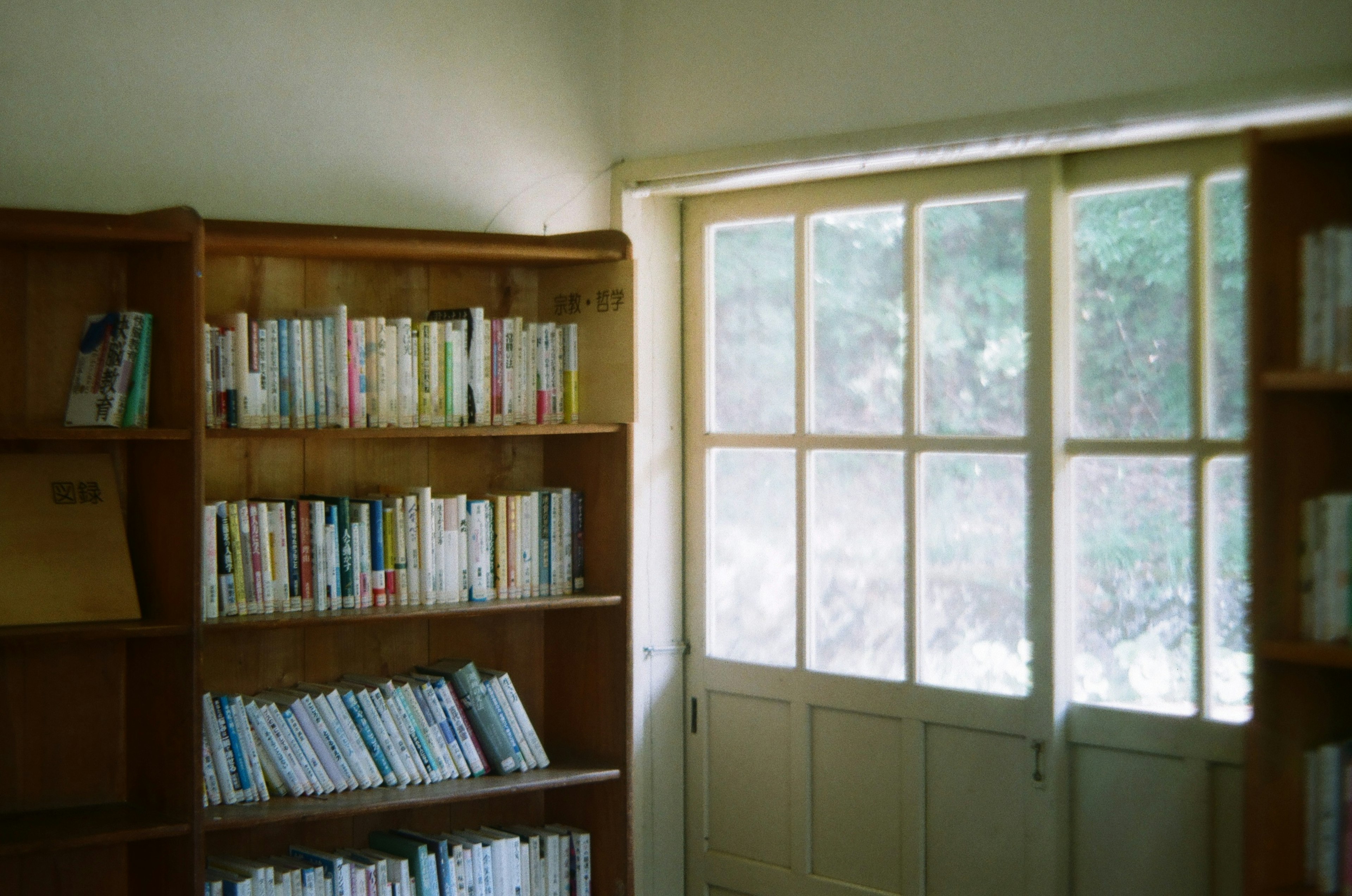 A quiet room with wooden bookshelves filled with books and natural light coming through the window