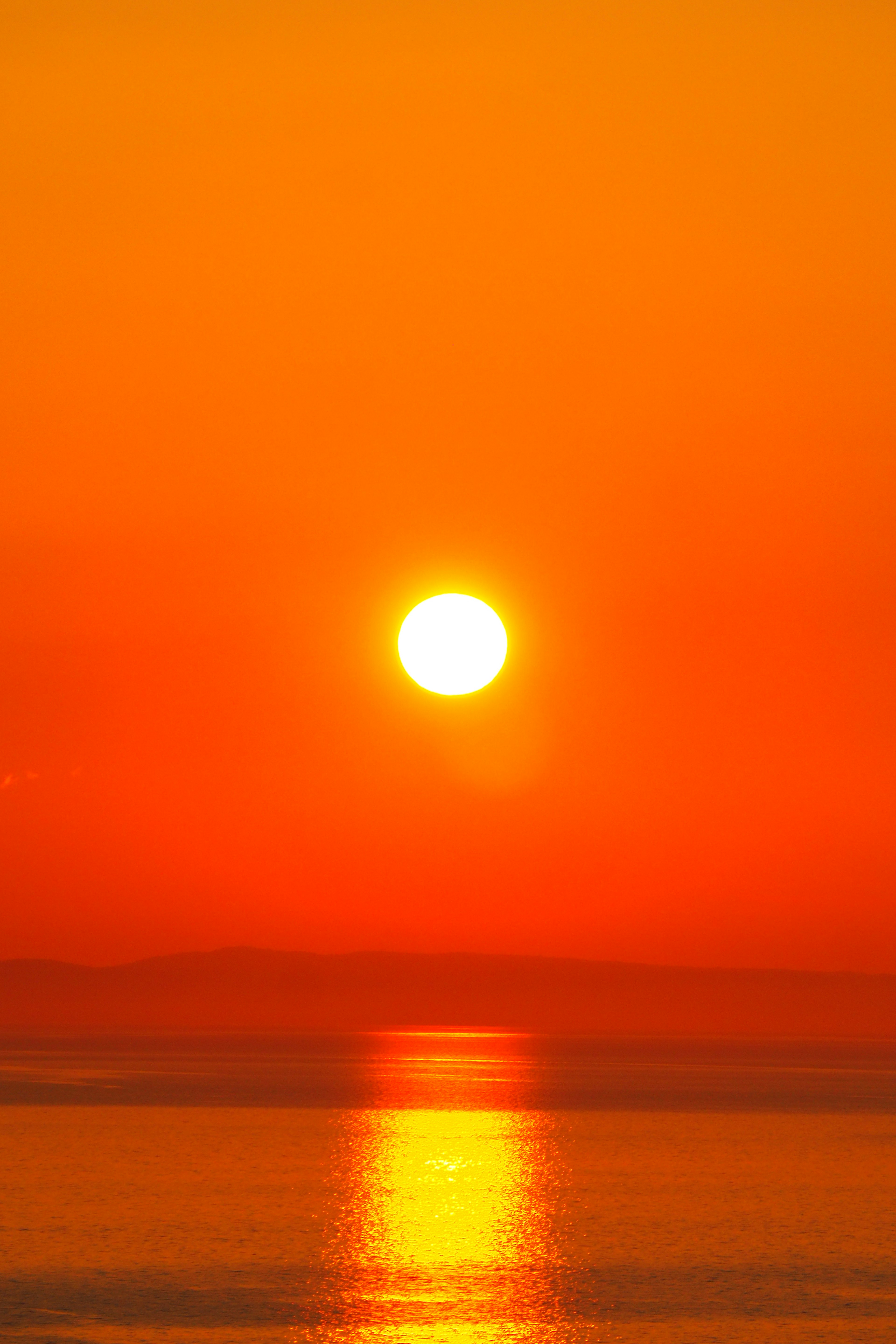 Schöner orangefarbener Sonnenuntergang, der sich im Meer spiegelt