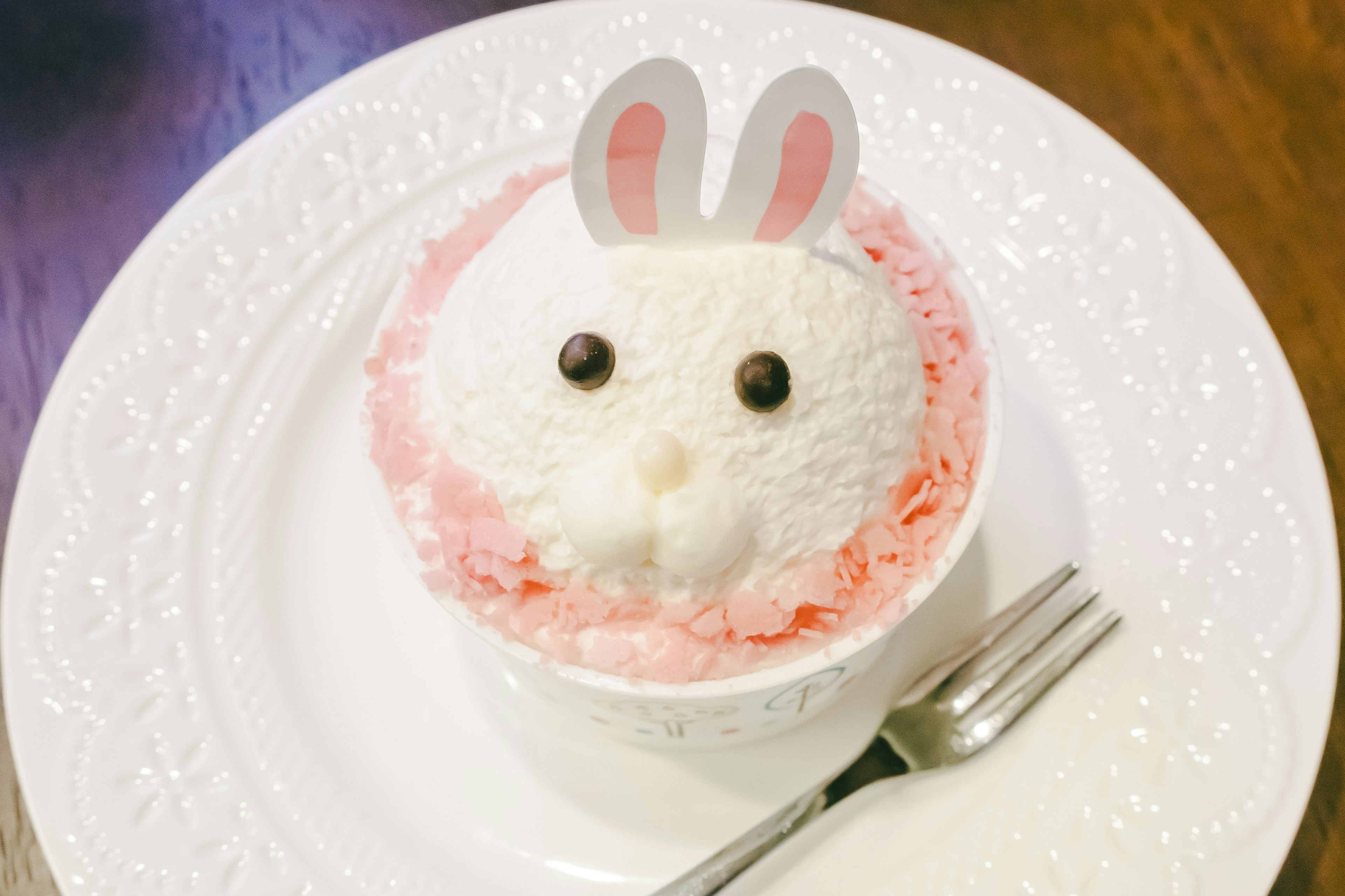 Niedriges Dessert im Hasenstil mit weißem Eis und rosa Sahne sowie Hasenohren-Dekoration