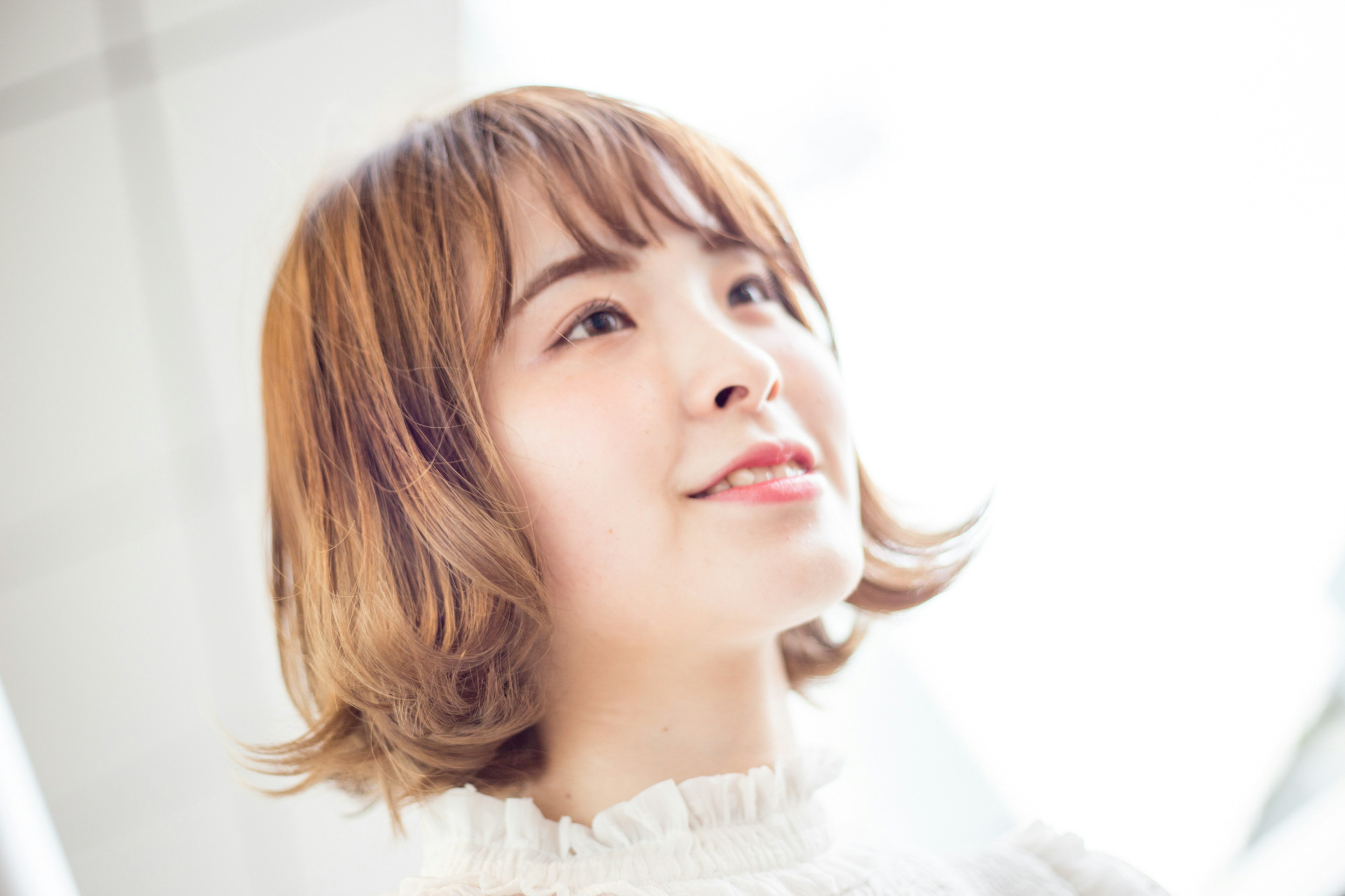 Retrato de una mujer sonriente con cabello corto contra un fondo brillante