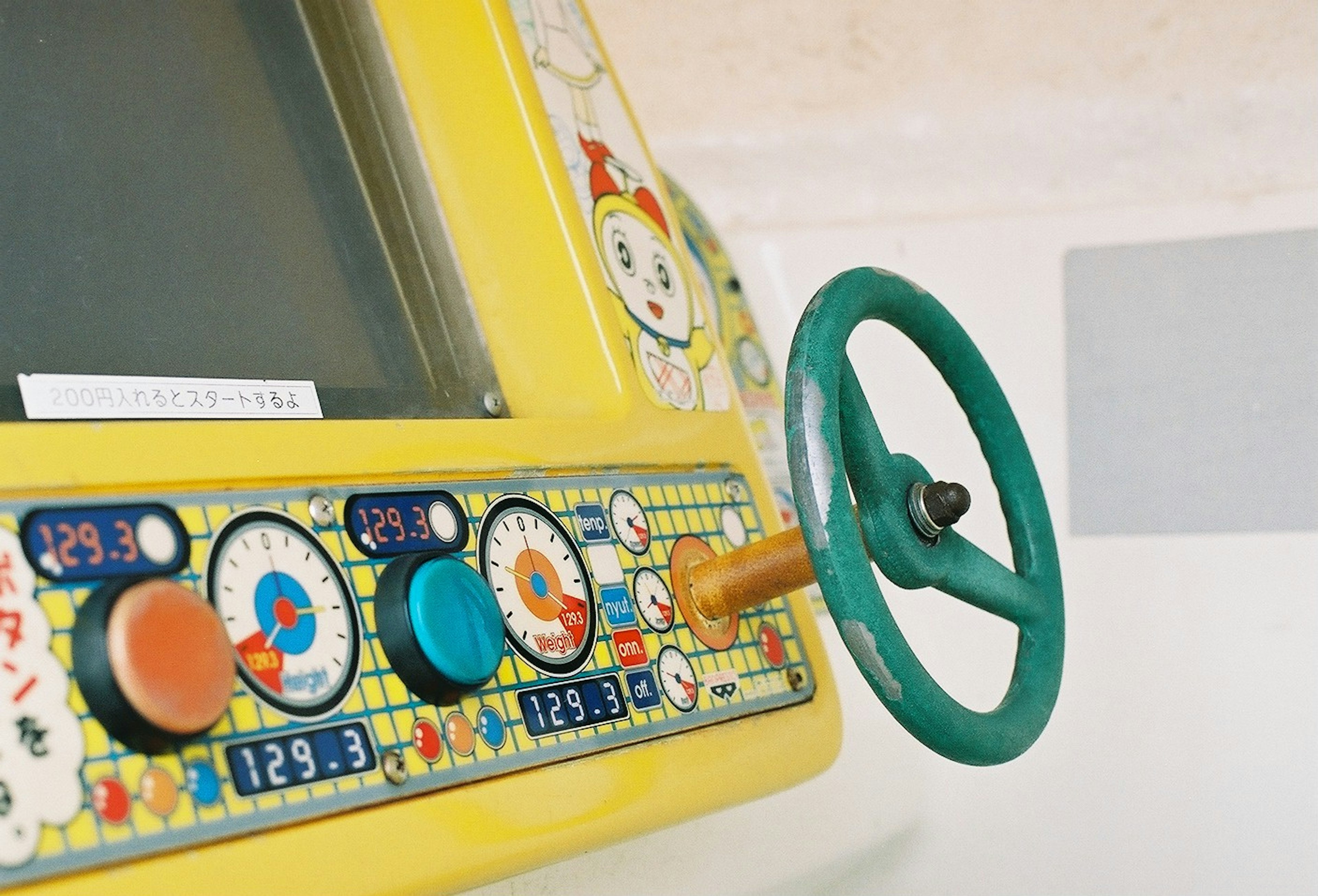 Pannello di controllo di una macchina gialla colorata con un volante verde e vari pulsanti