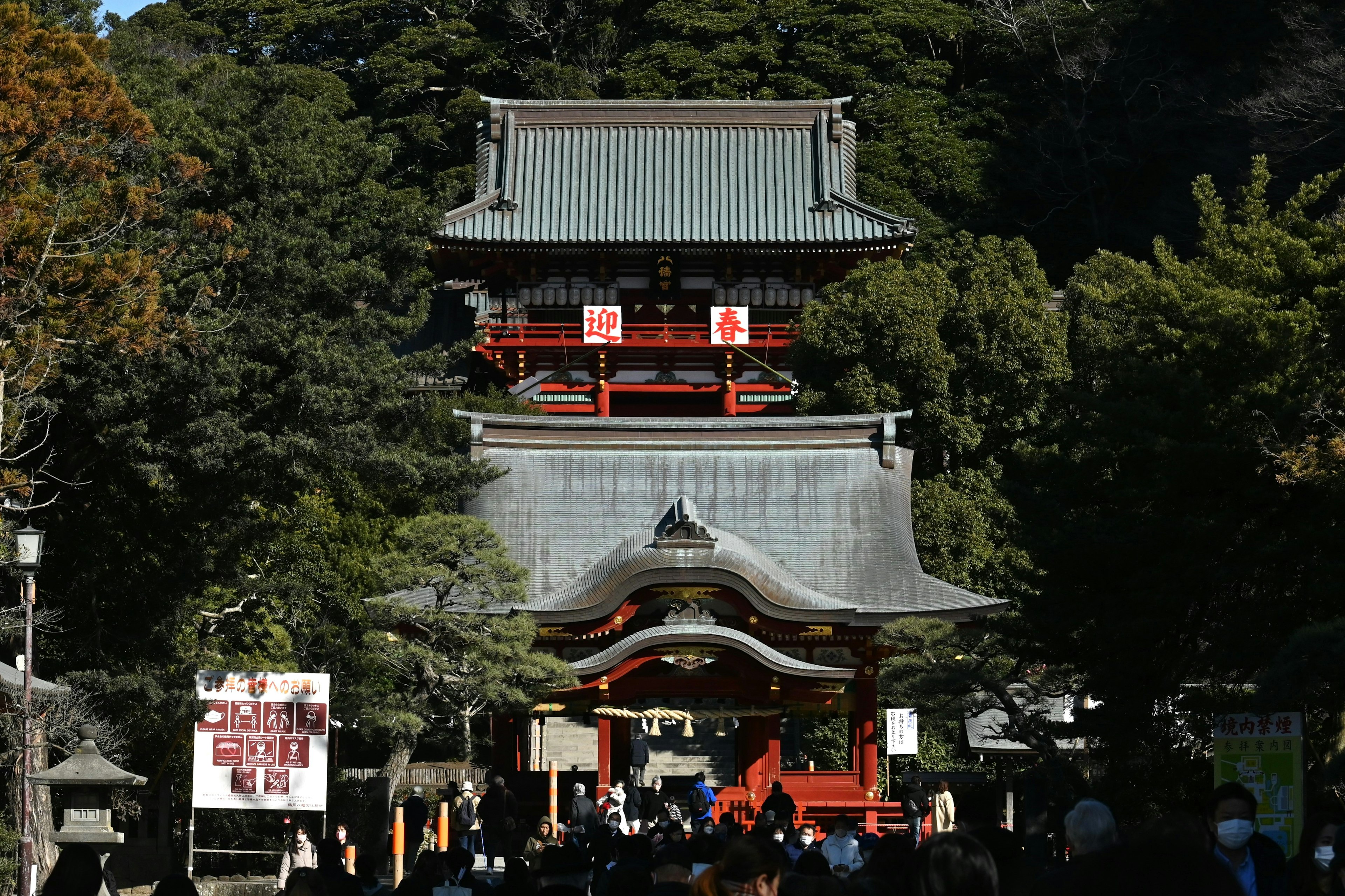 被綠色環繞的紅色寺廟門和三層寶塔的風景