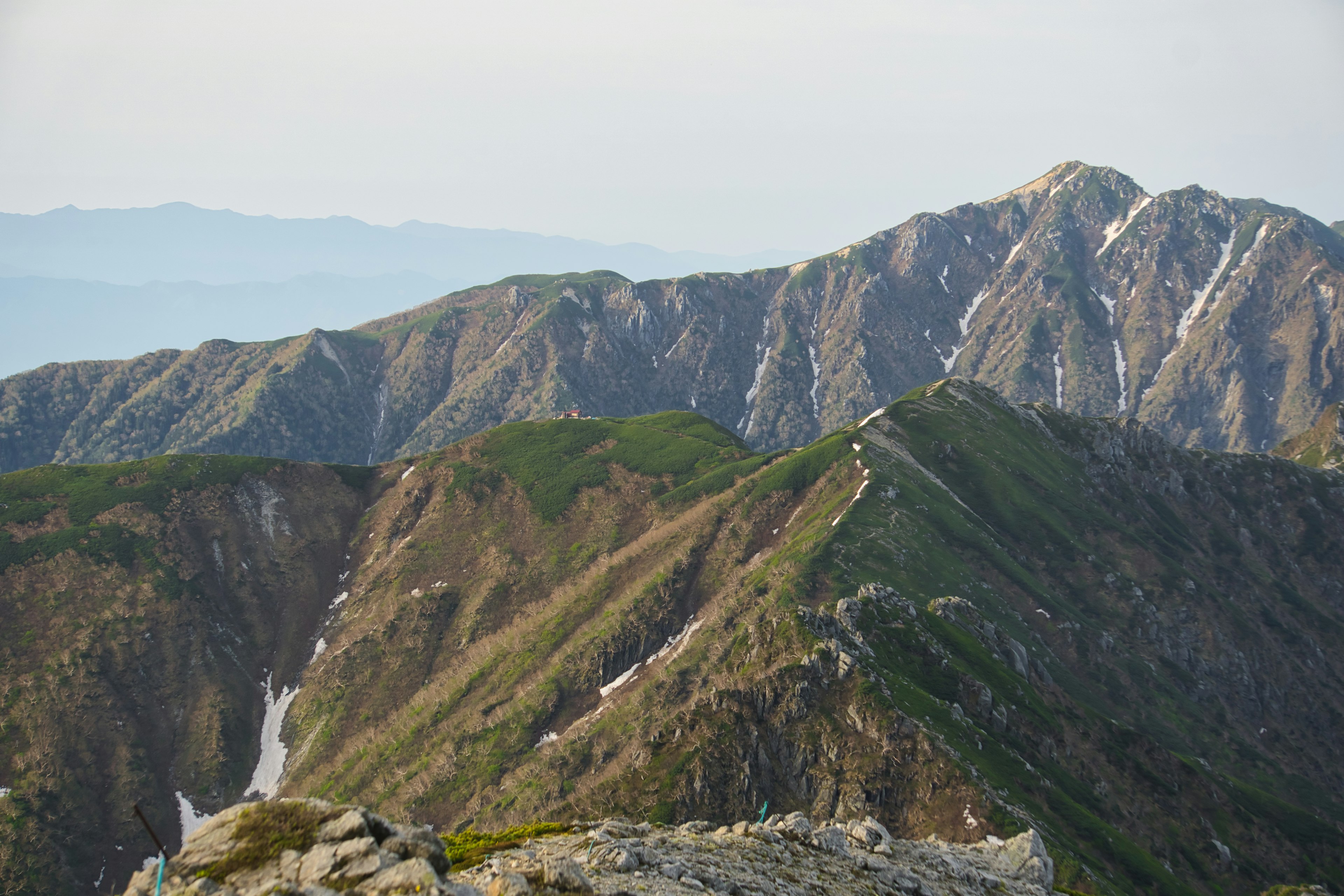 Paysage de montagne avec des pentes verdoyantes et des sommets enneigés