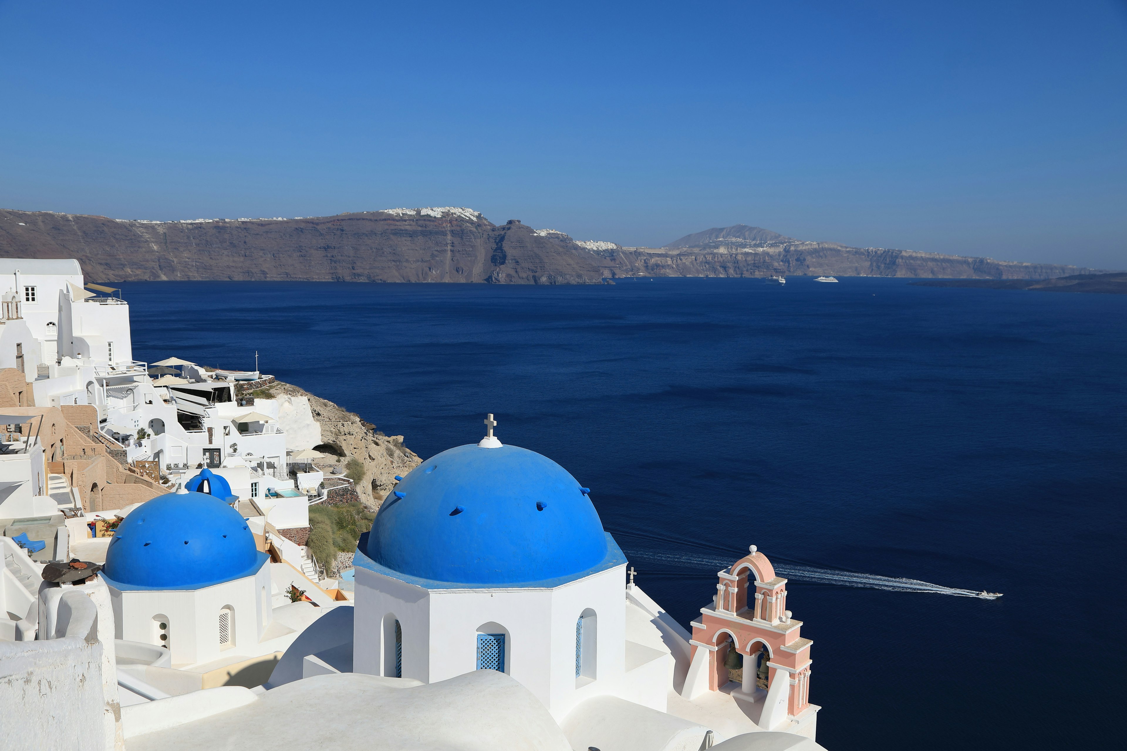 Cảnh bờ biển Santorini với những tòa nhà trắng và mái vòm xanh