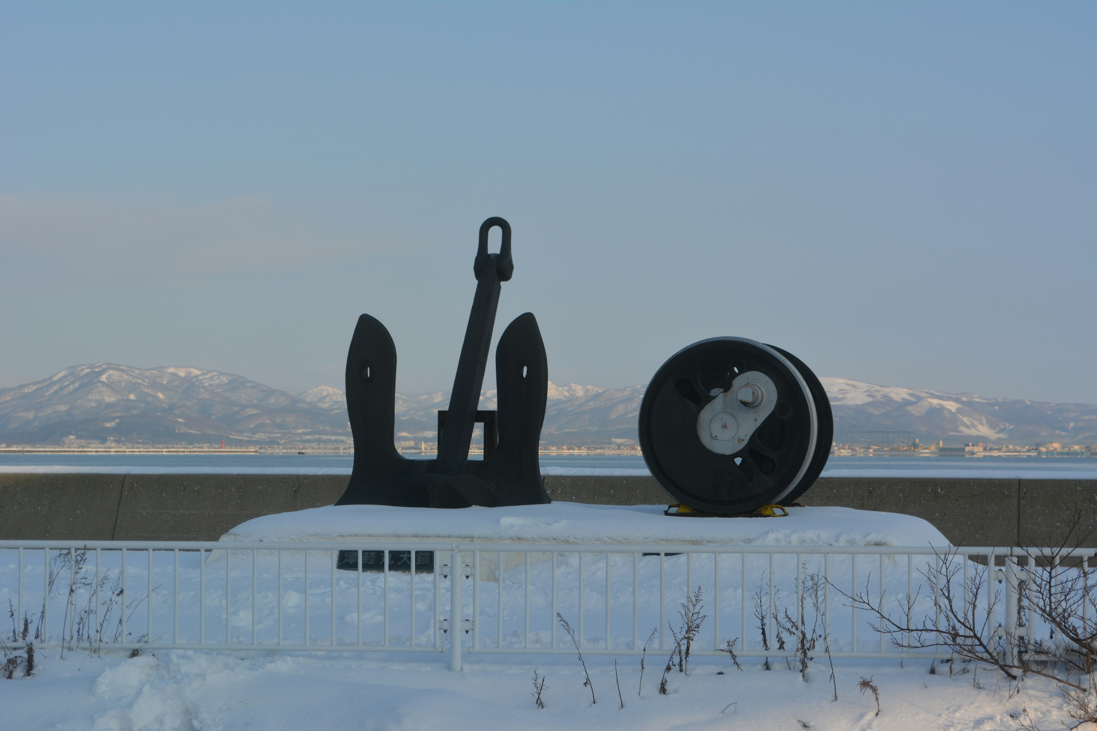 Black anchor and circular object on a snowy background