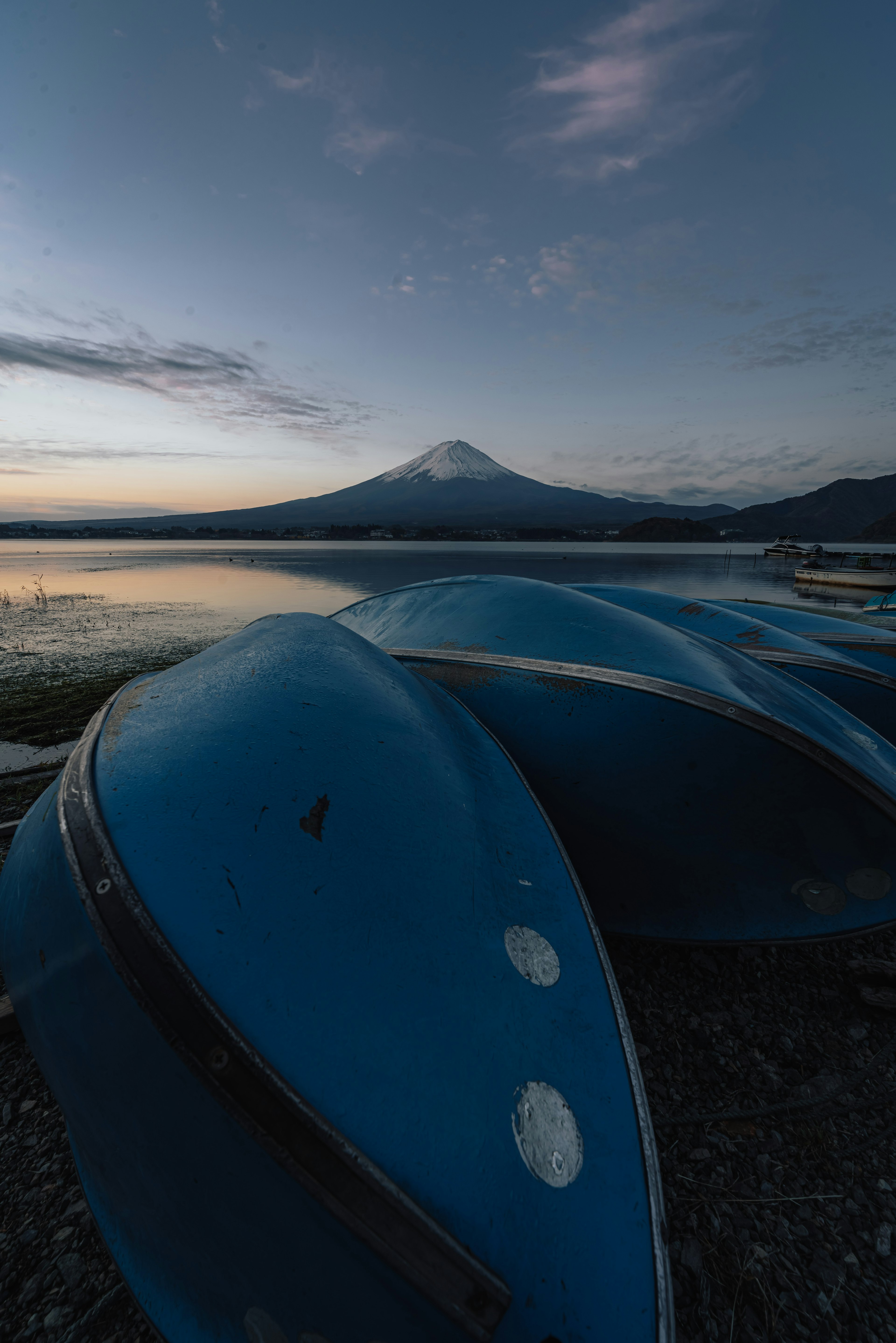 青いボートが湖の岸辺に並び、背景には美しい富士山が広がる