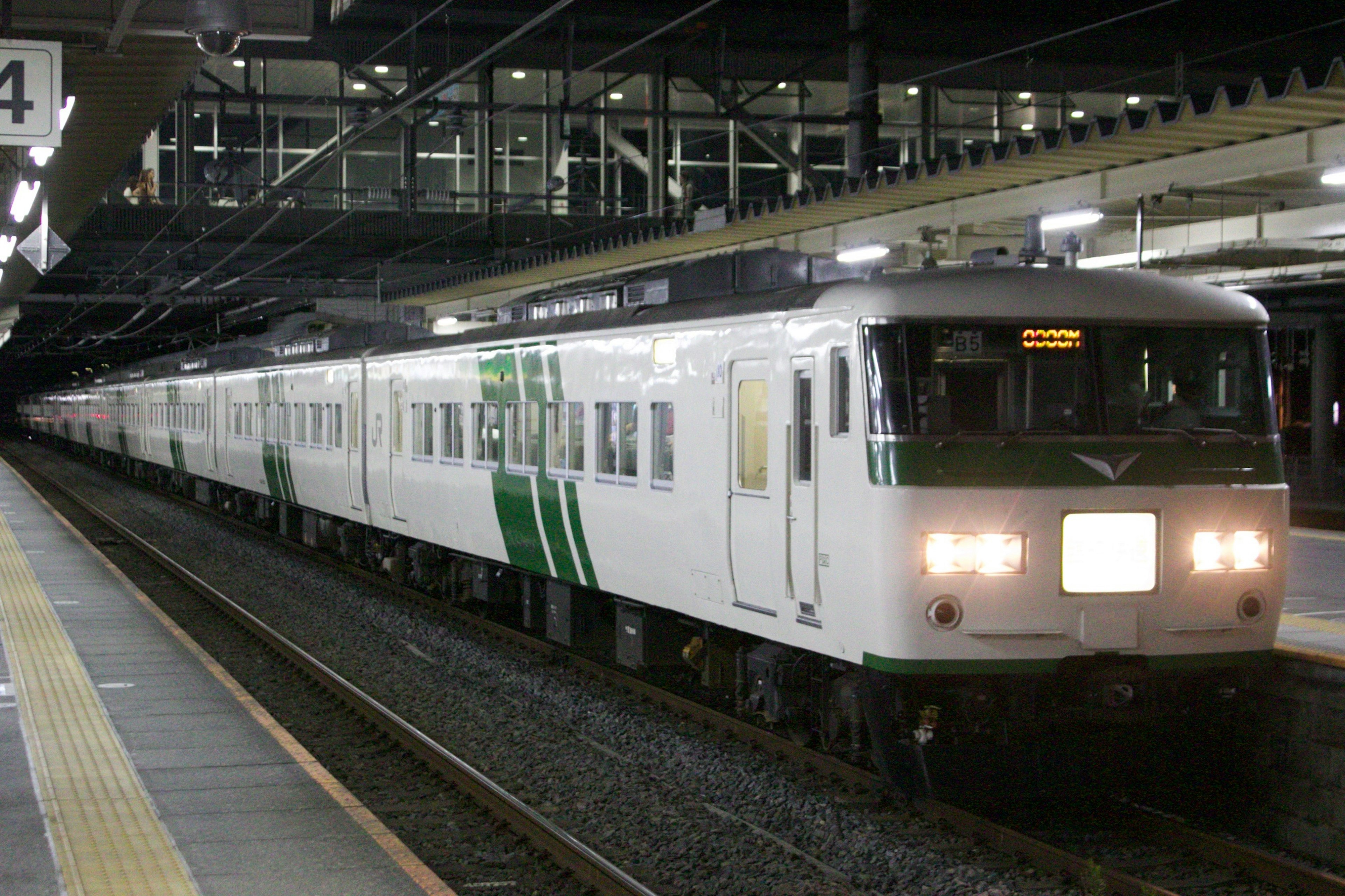 白と緑のデザインの電車が駅に停車している