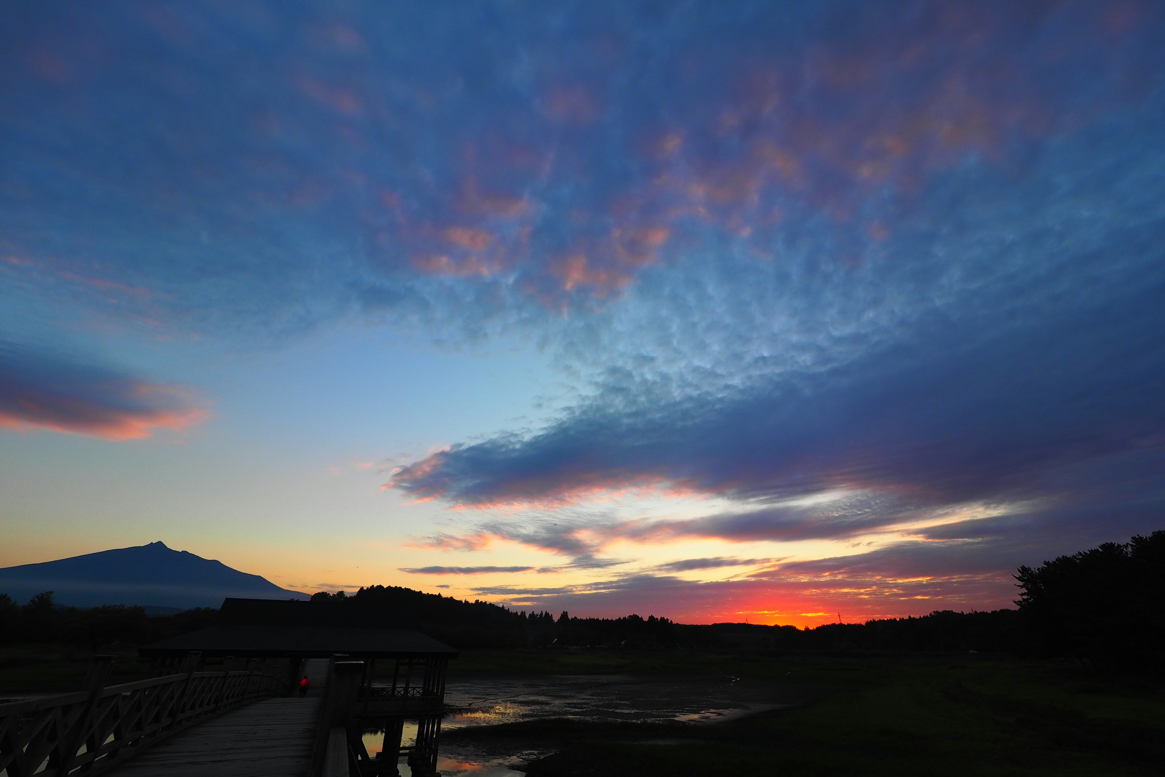 Pemandangan indah dengan langit senja dan siluet gunung di air tenang