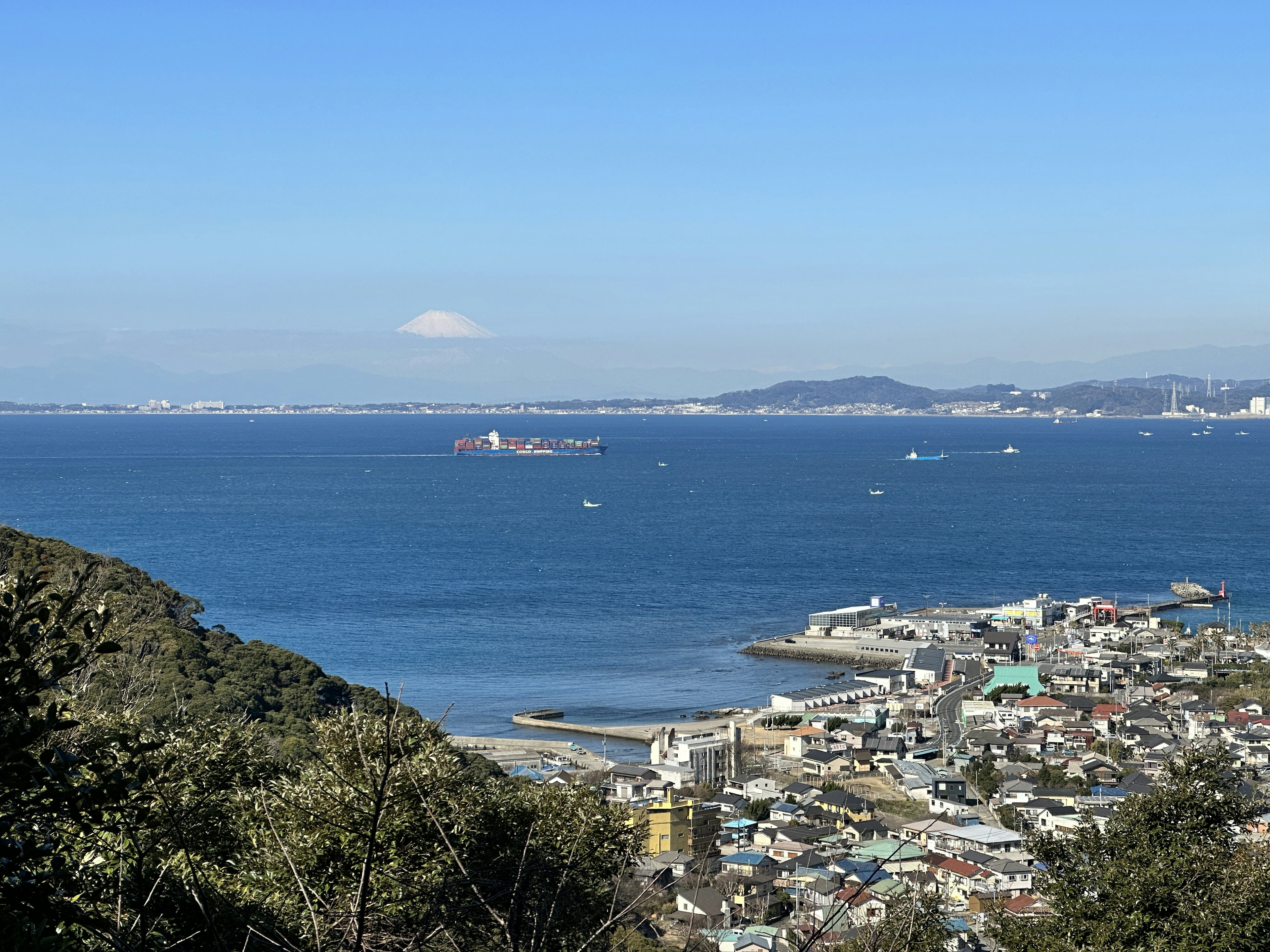 Scenic view of a coastal town with blue ocean and distant mountains