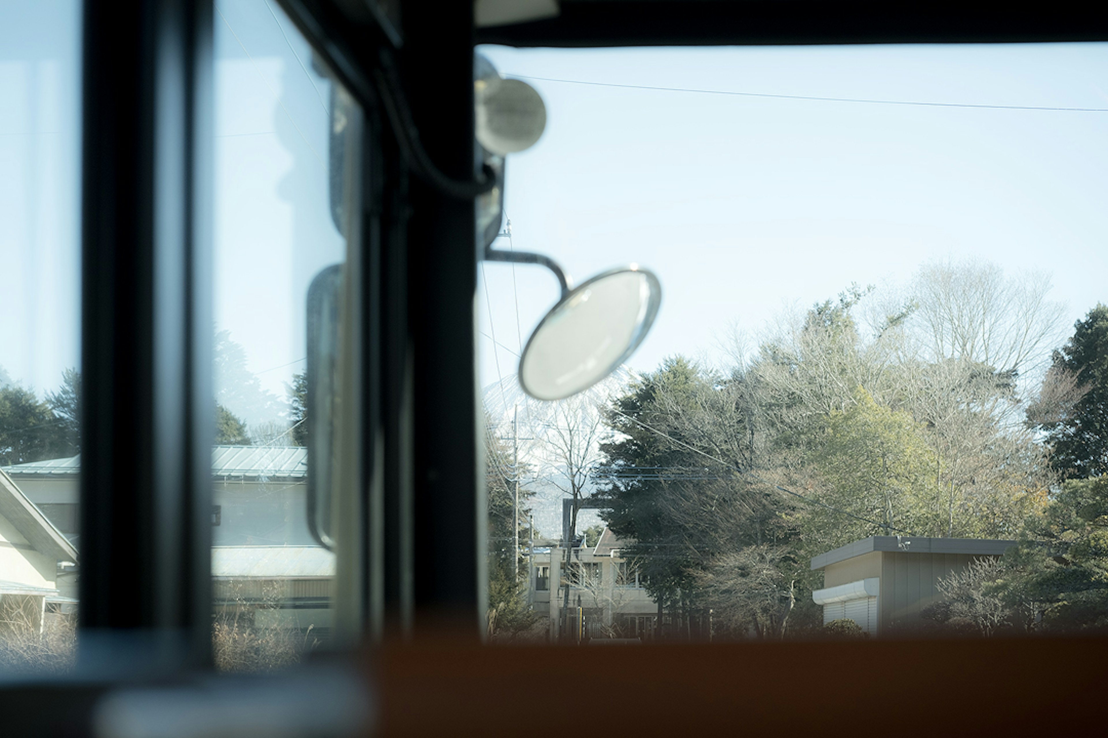 View through a bus window showing landscape and mirror