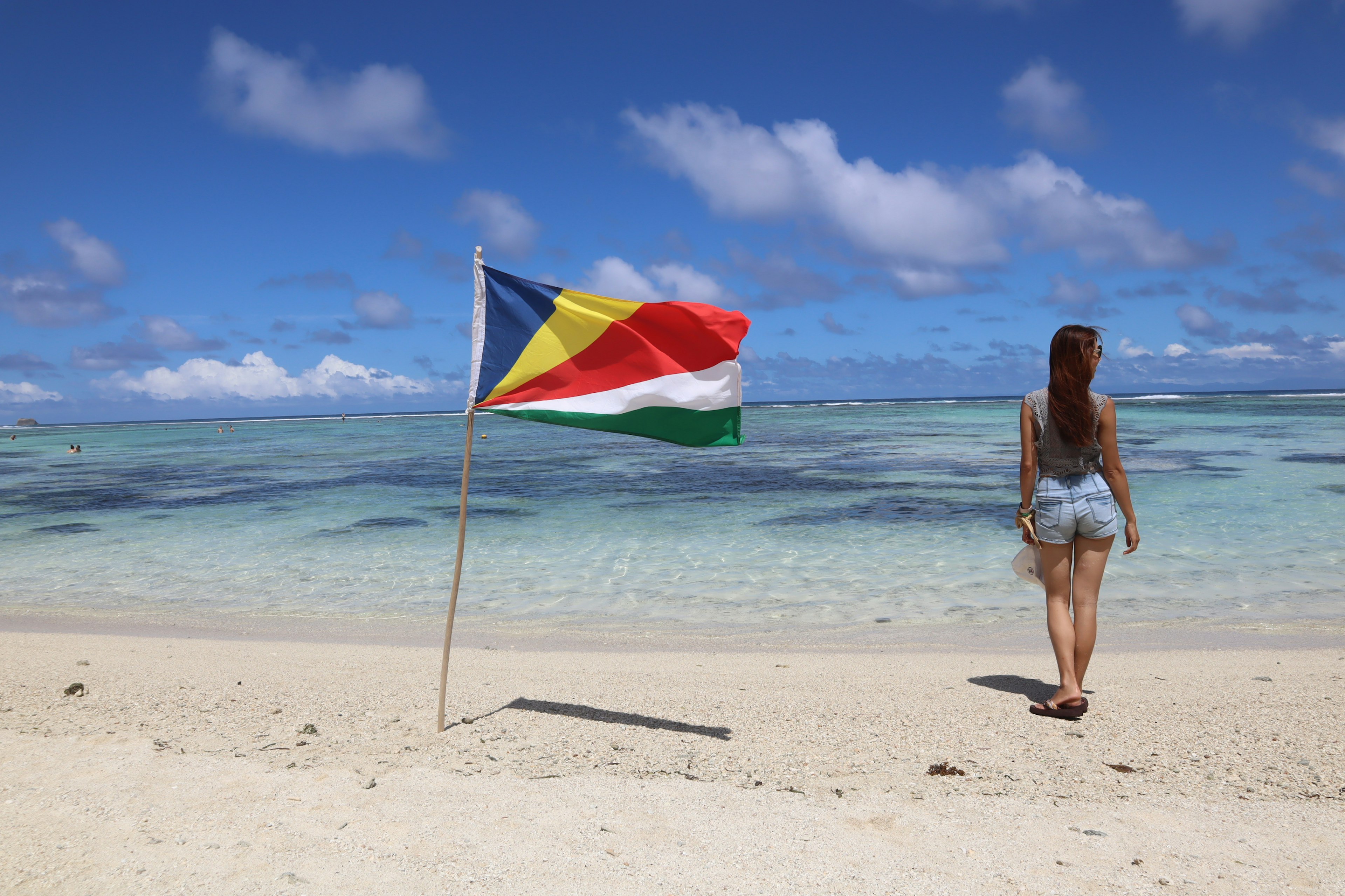 Woman walking on the beach near the Seychelles flag