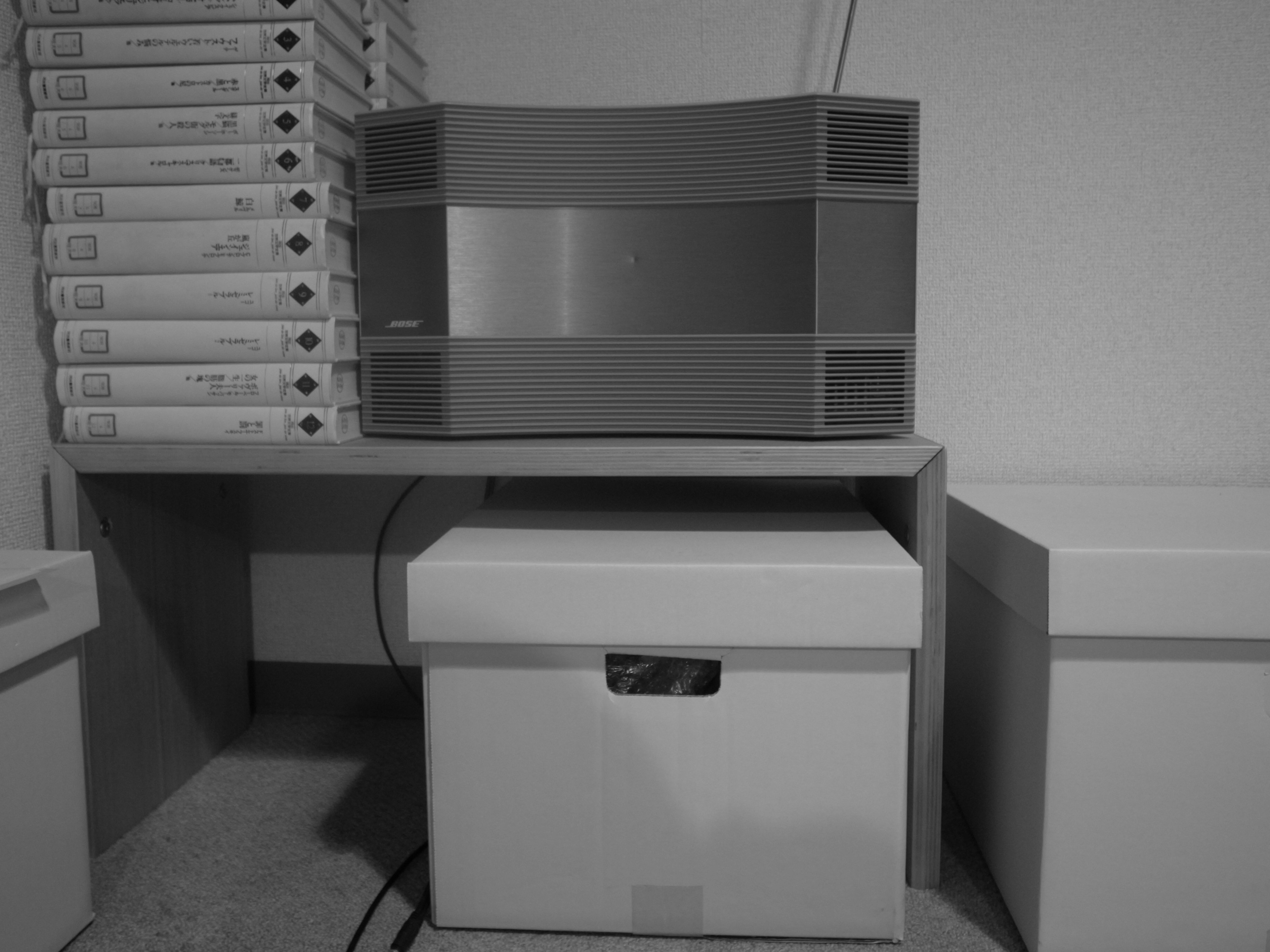 Black and white image of a storage box with a speaker on a shelf