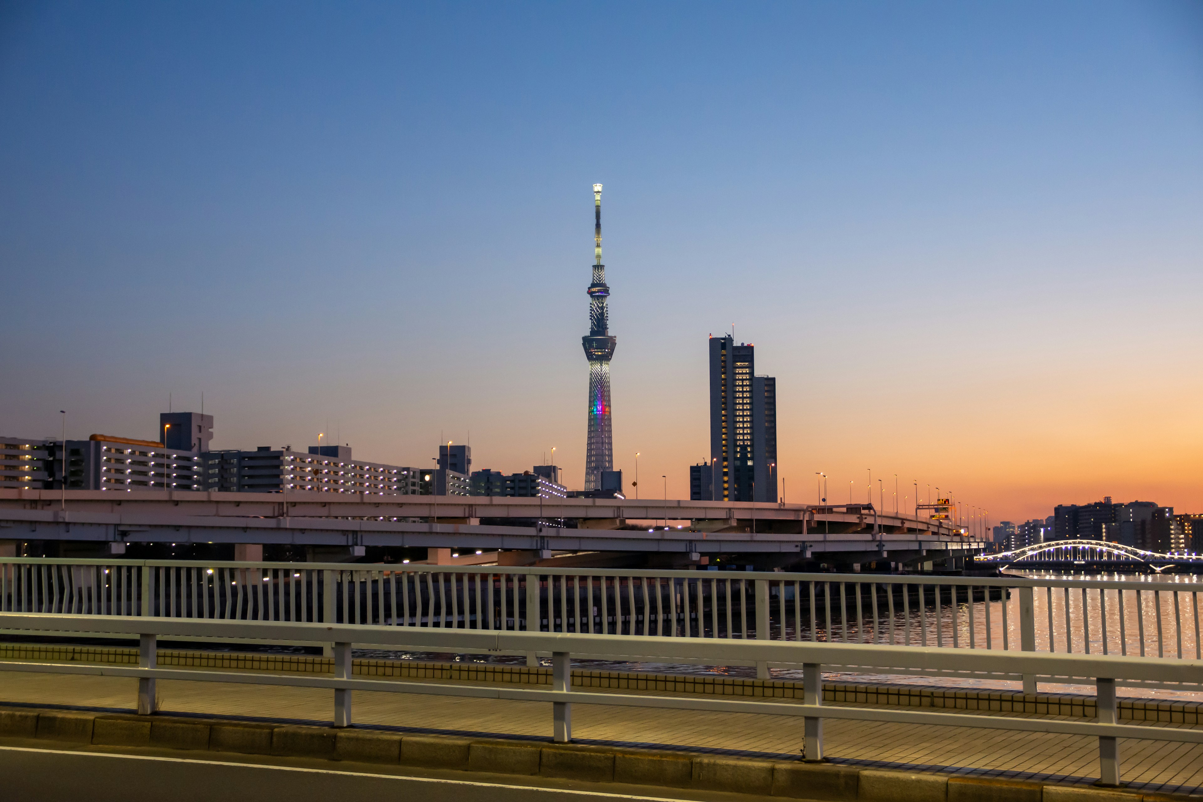 Tokyo Skytree saat senja dengan gedung-gedung terdekat dan sungai