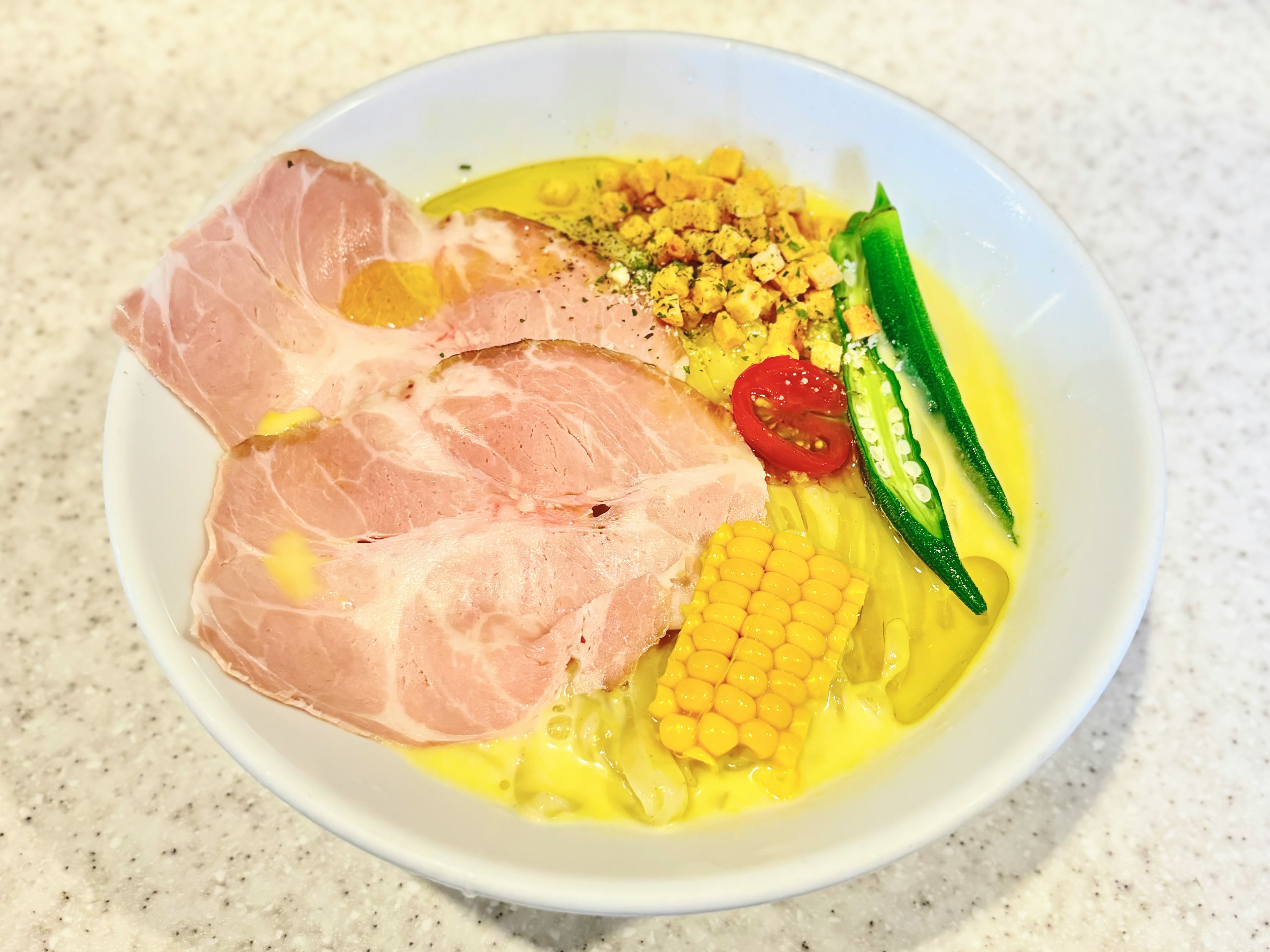 Un bol de ramen délicieux garni de porc tranché, de maïs, de gombo, de tomate et d'œuf