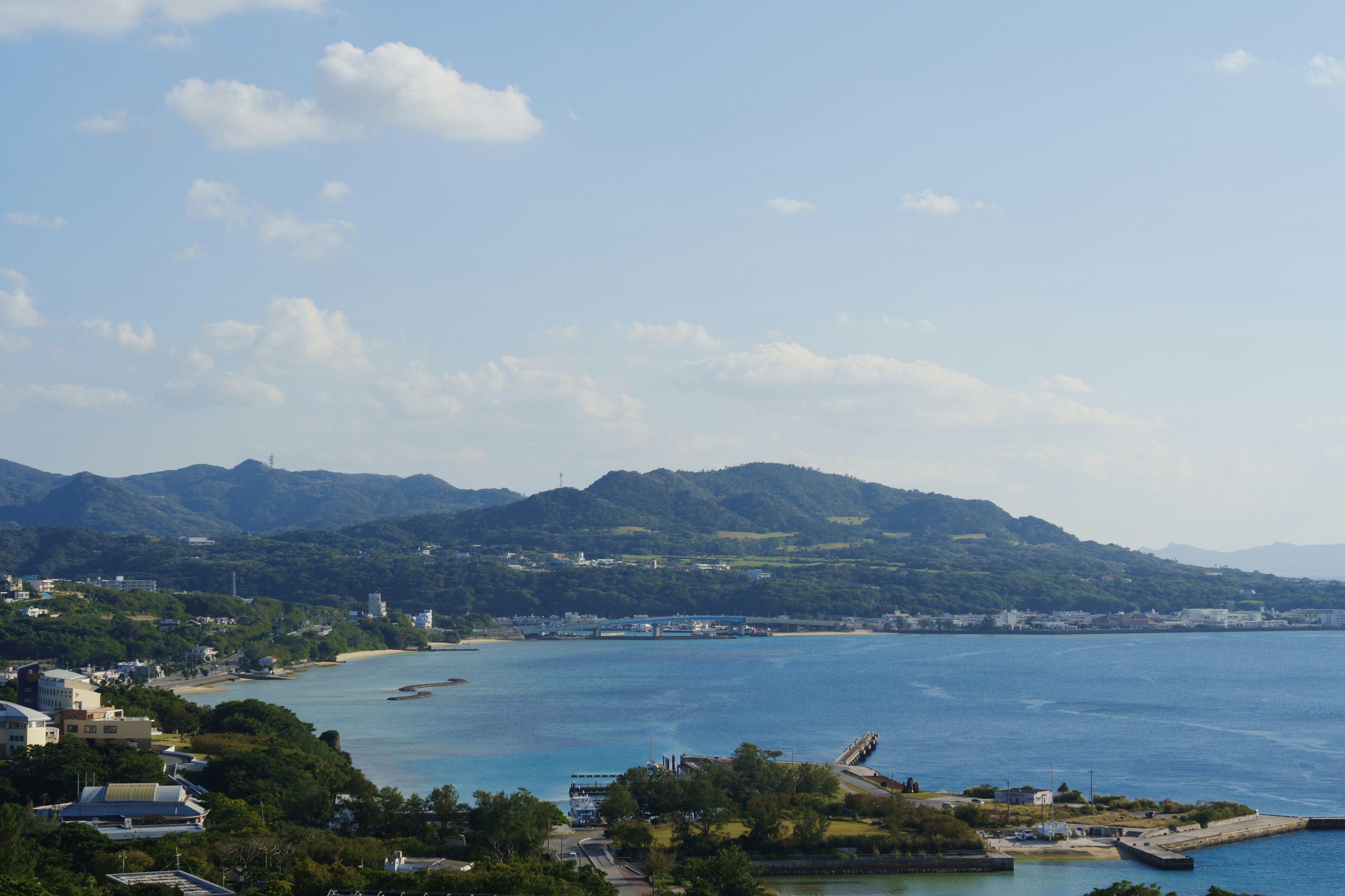 Scenic view of blue ocean and green hills under a clear sky