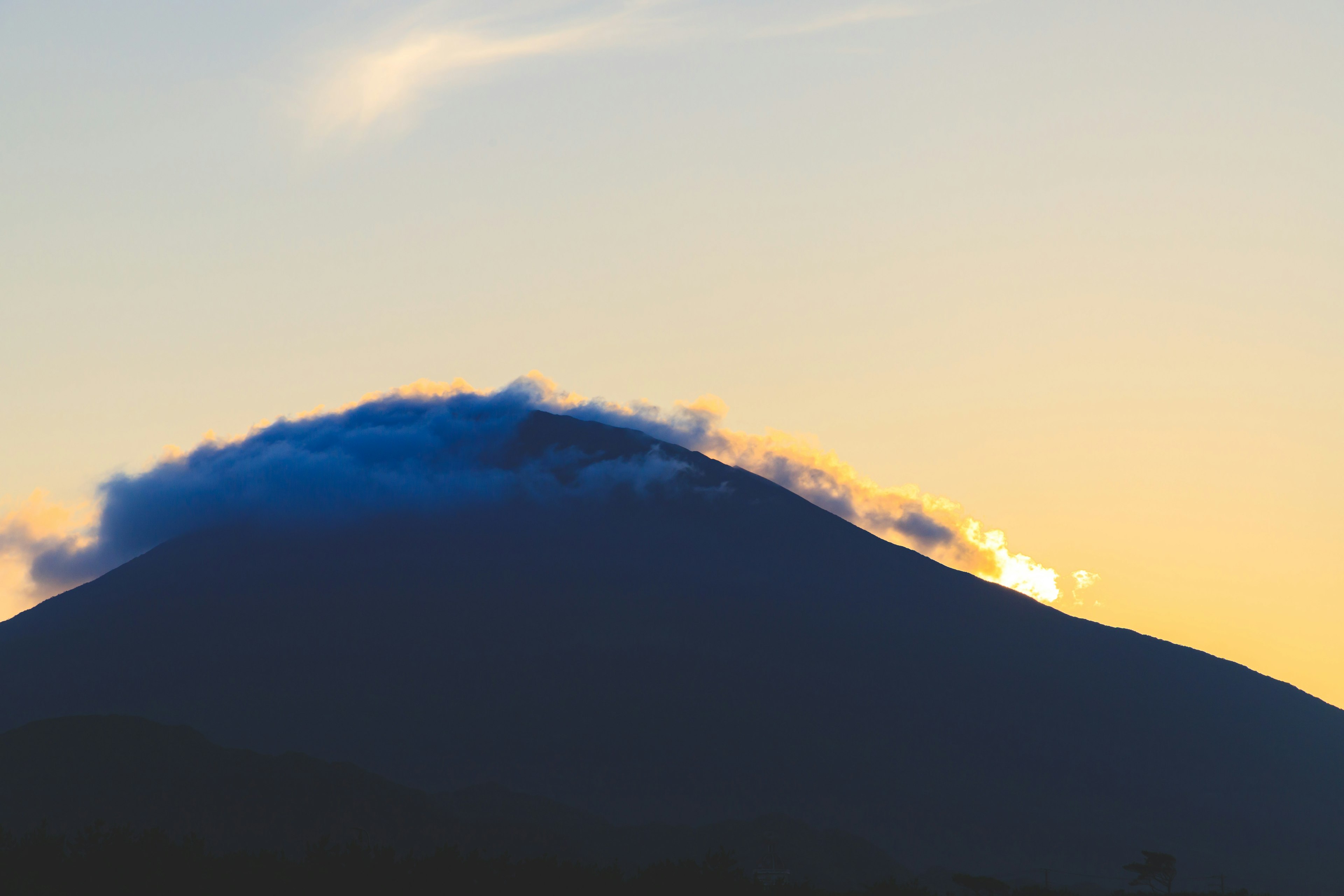 山の頂上には雲がかかり夕焼けの空の中で美しい景色を作り出している