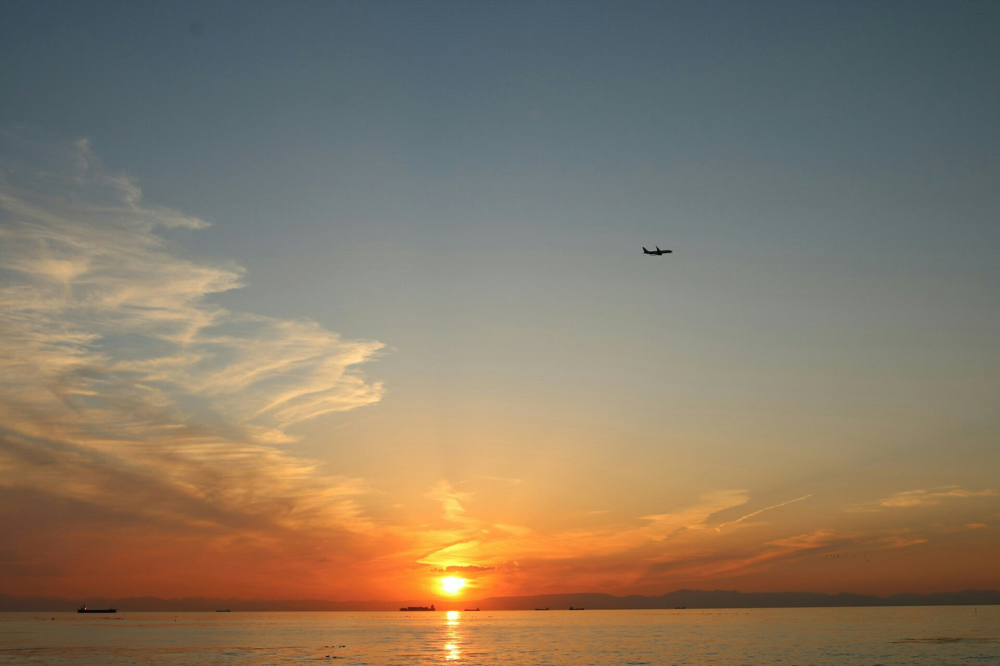 Beautiful landscape of sunset over the ocean with an airplane in the sky