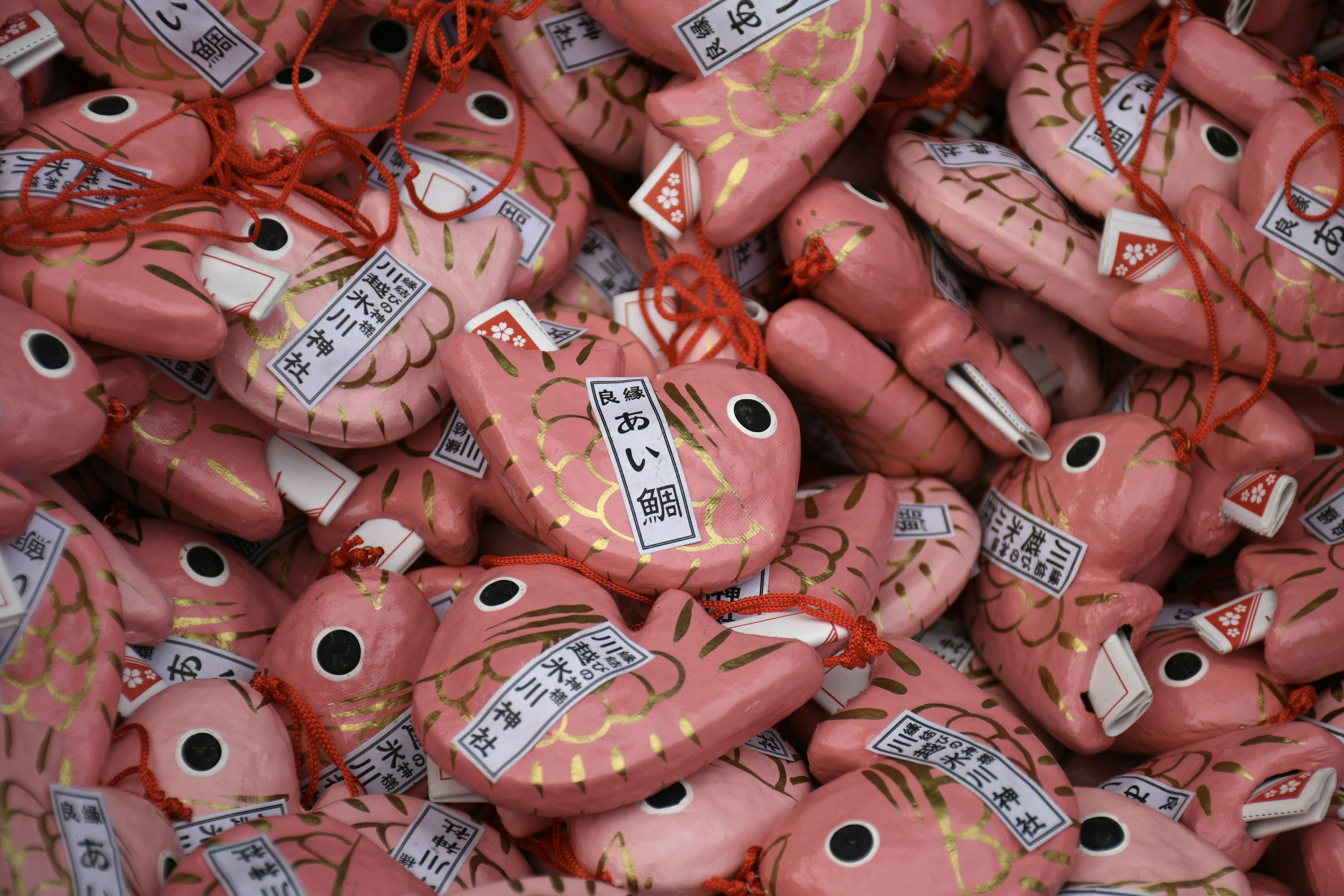 A collection of pink fish-shaped amulets with inscriptions