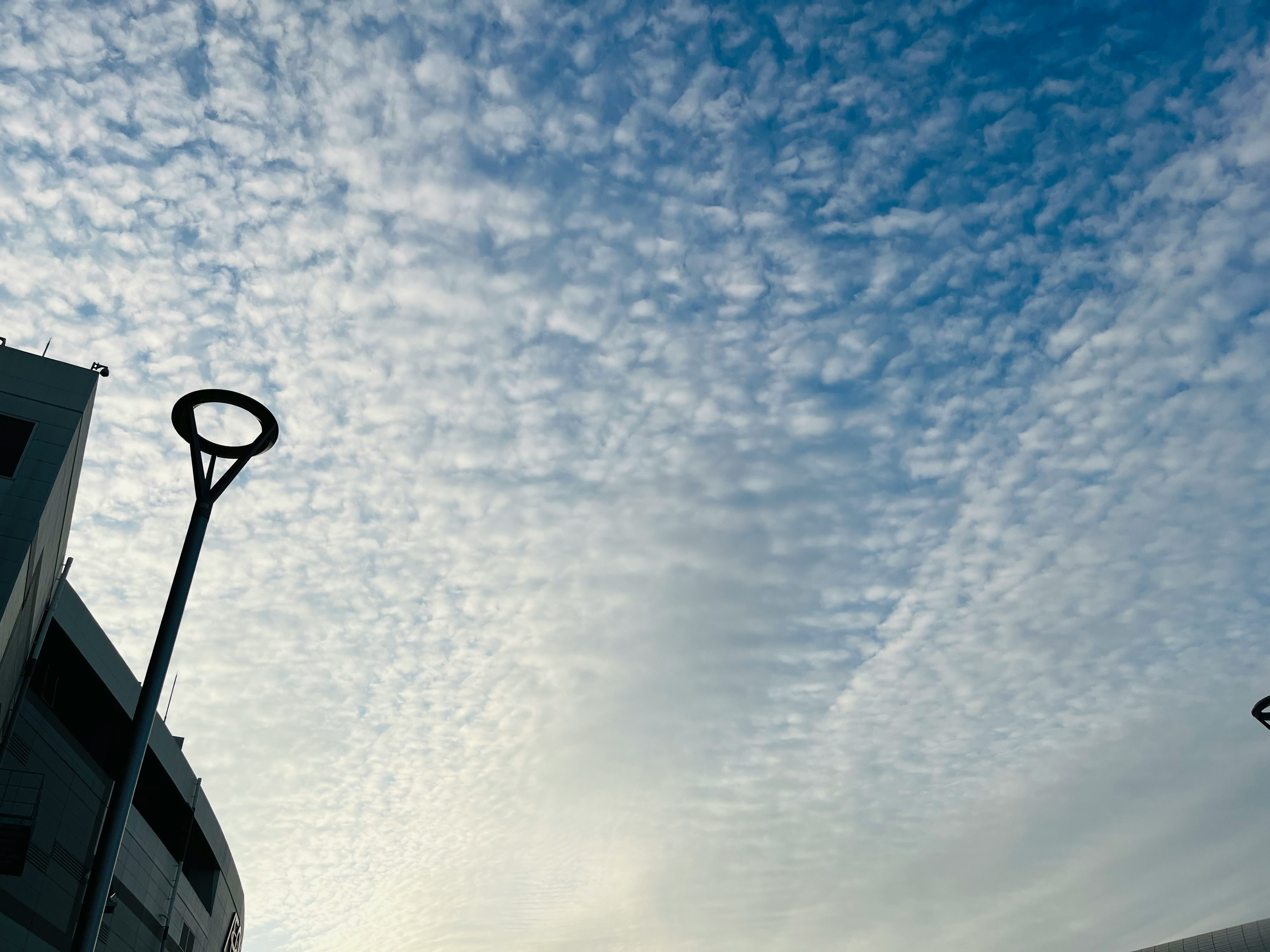 Silhouette d'un lampadaire contre un ciel nuageux bleu