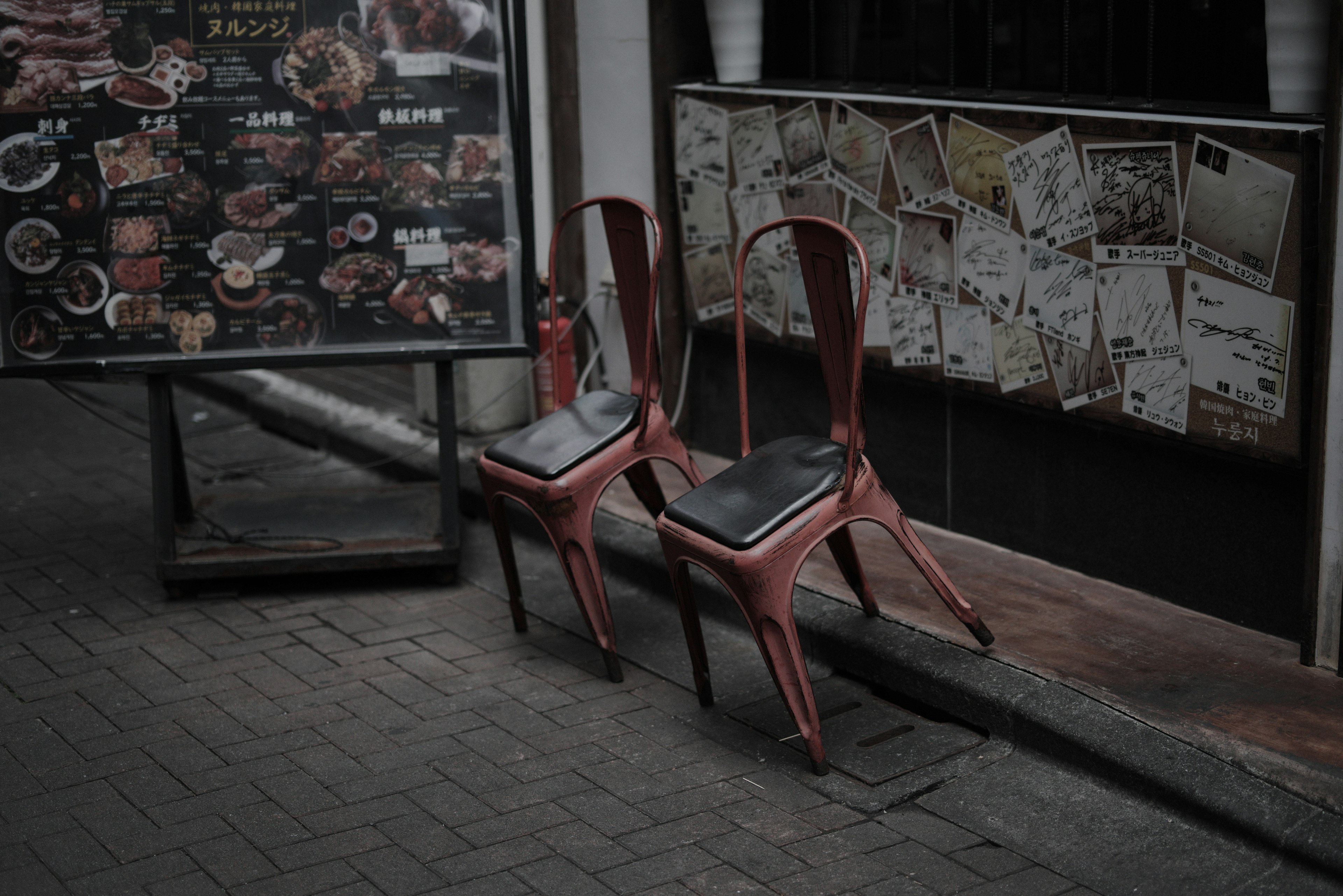 Photo de deux chaises rouges devant un restaurant avec un panneau de menu