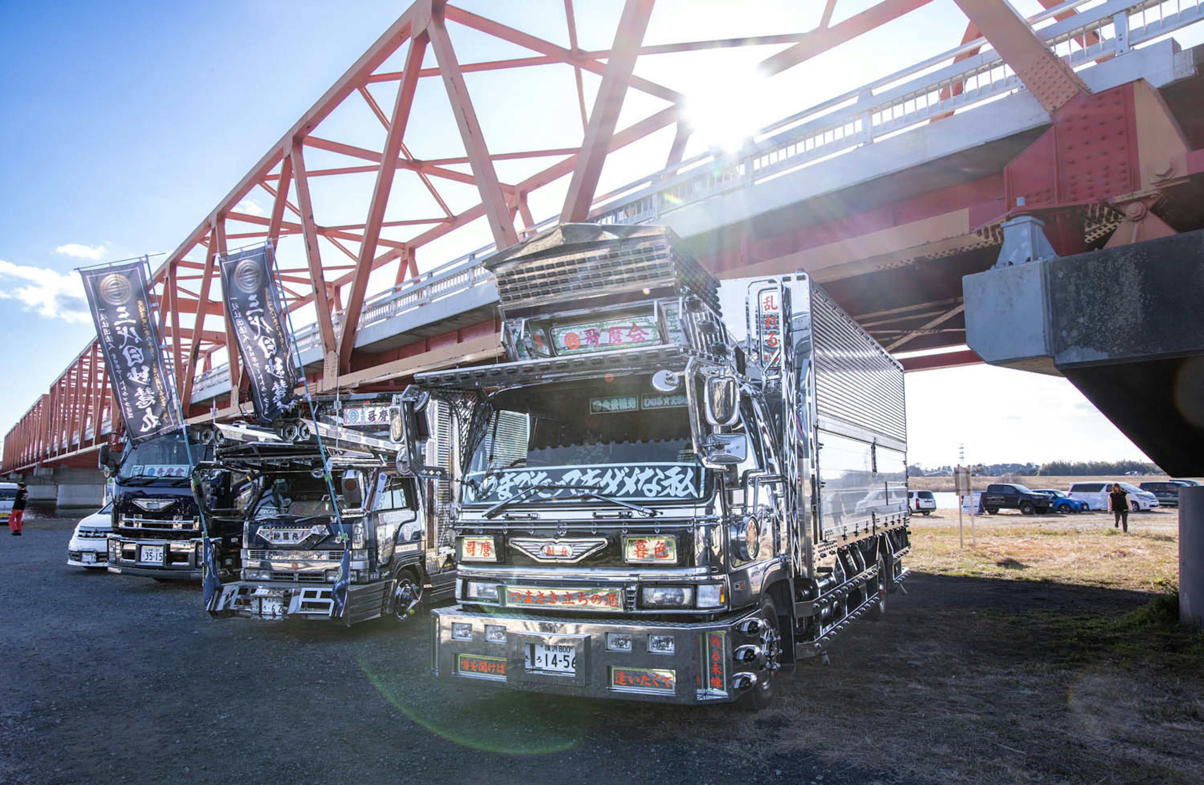 Decorated trucks parked under a red bridge