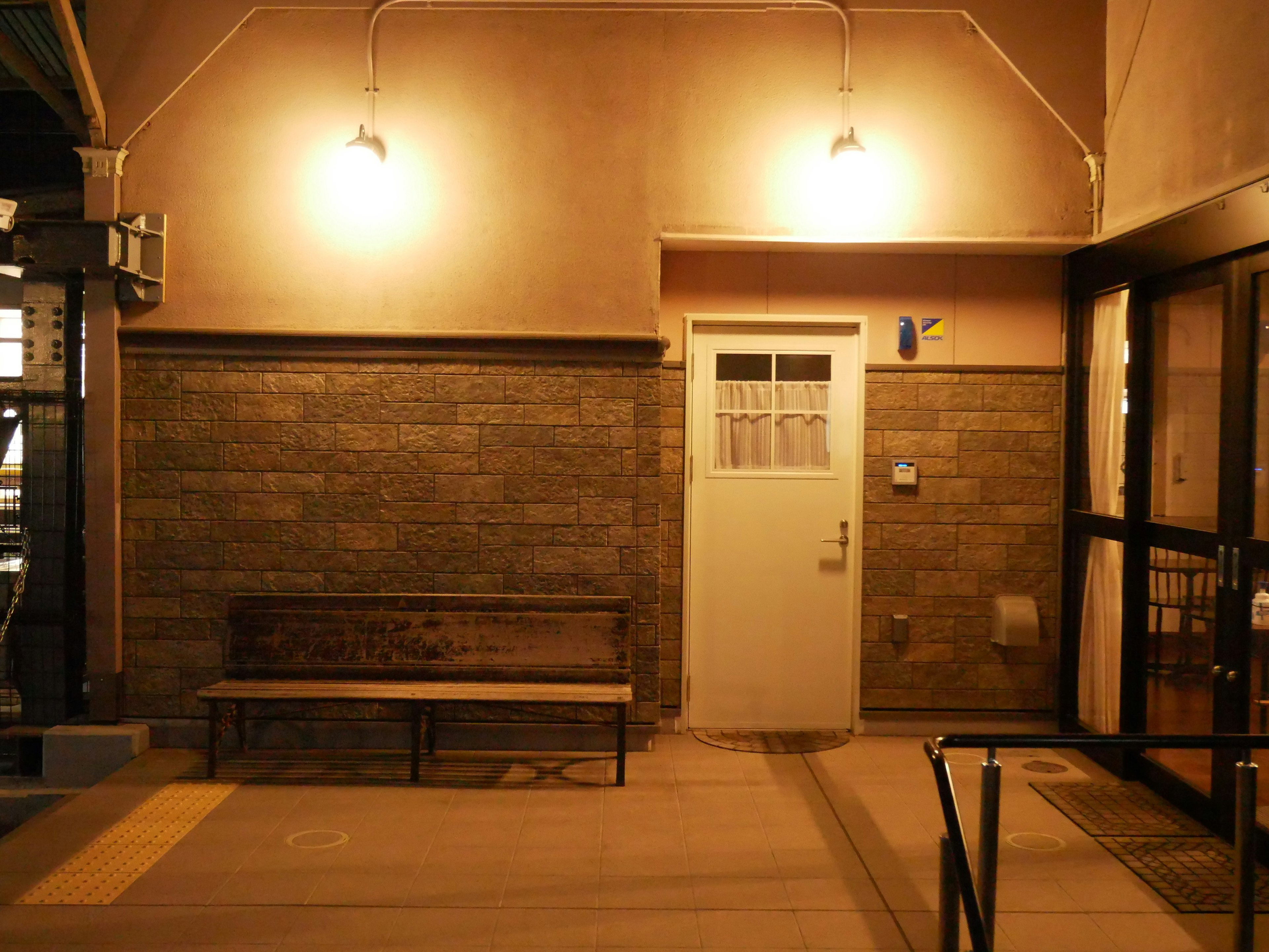 Entrée illuminée d'une salle d'attente de gare avec un banc en bois