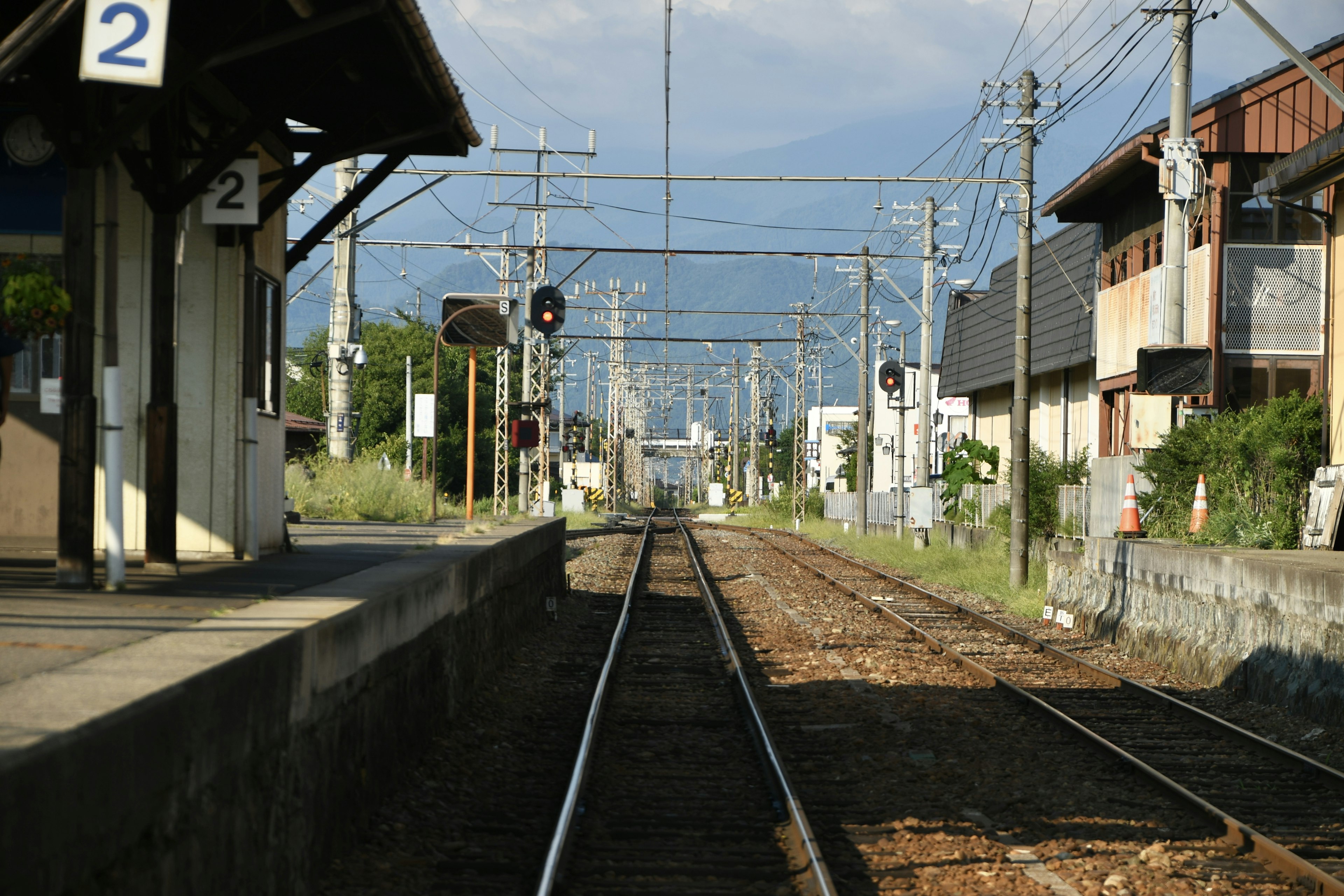 静かな駅のプラットフォームから見た鉄道の風景 線路が続き周囲に家々が並ぶ