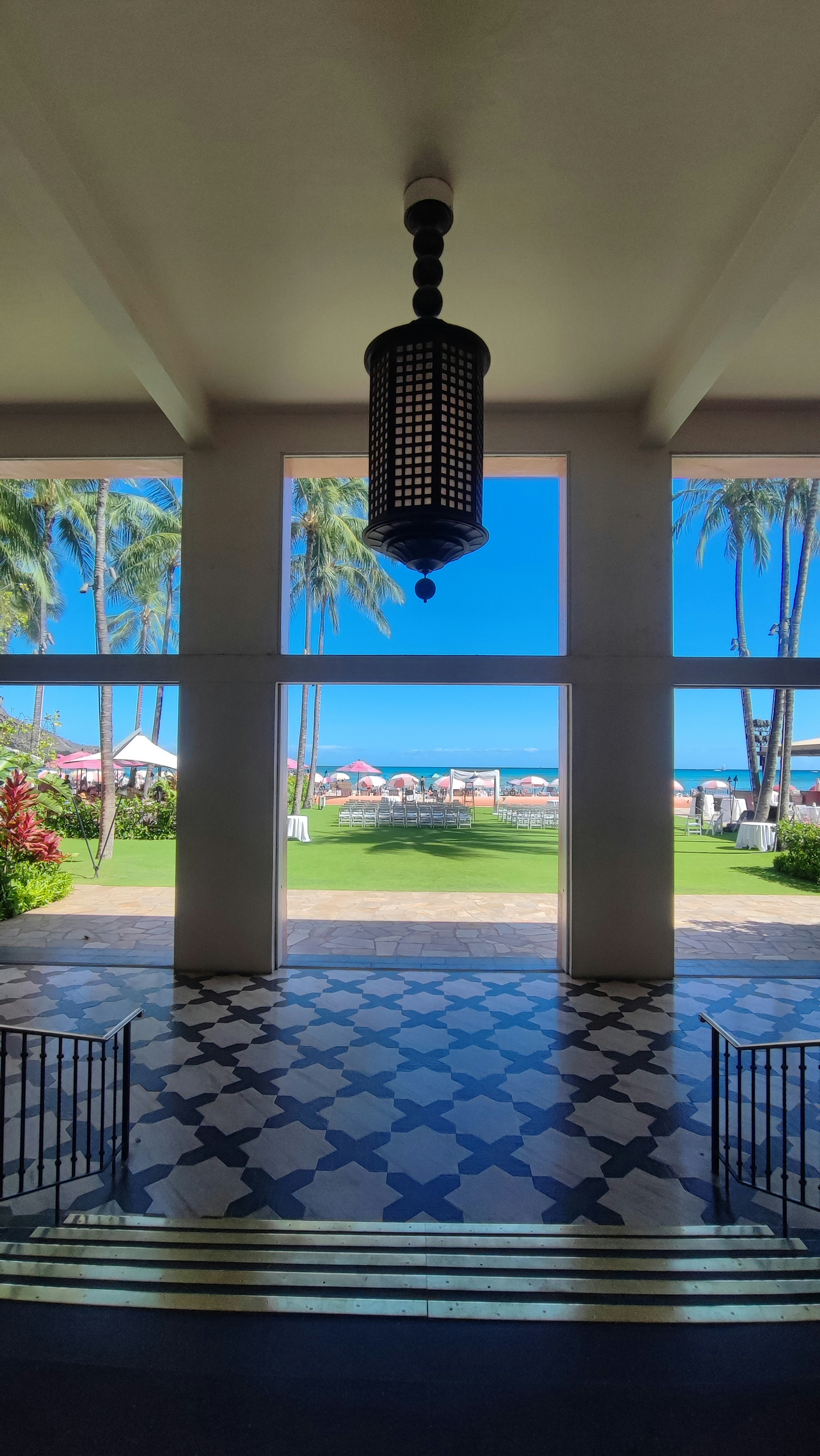 Vista de entrada abierta mostrando mar y cielo azules con lámpara decorativa y suelo de azulejos