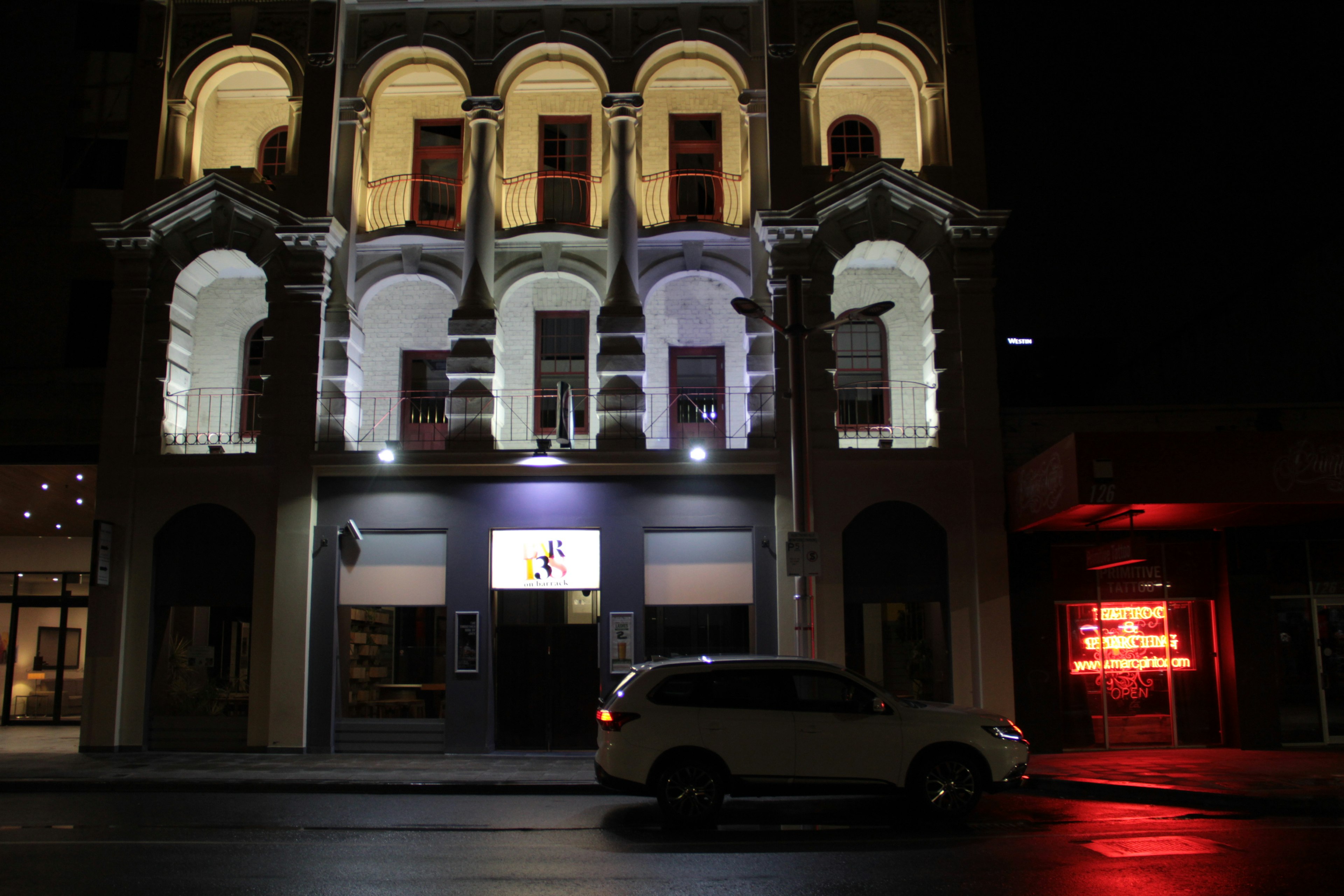 Façade élégante d'un bâtiment la nuit avec une voiture blanche garée devant