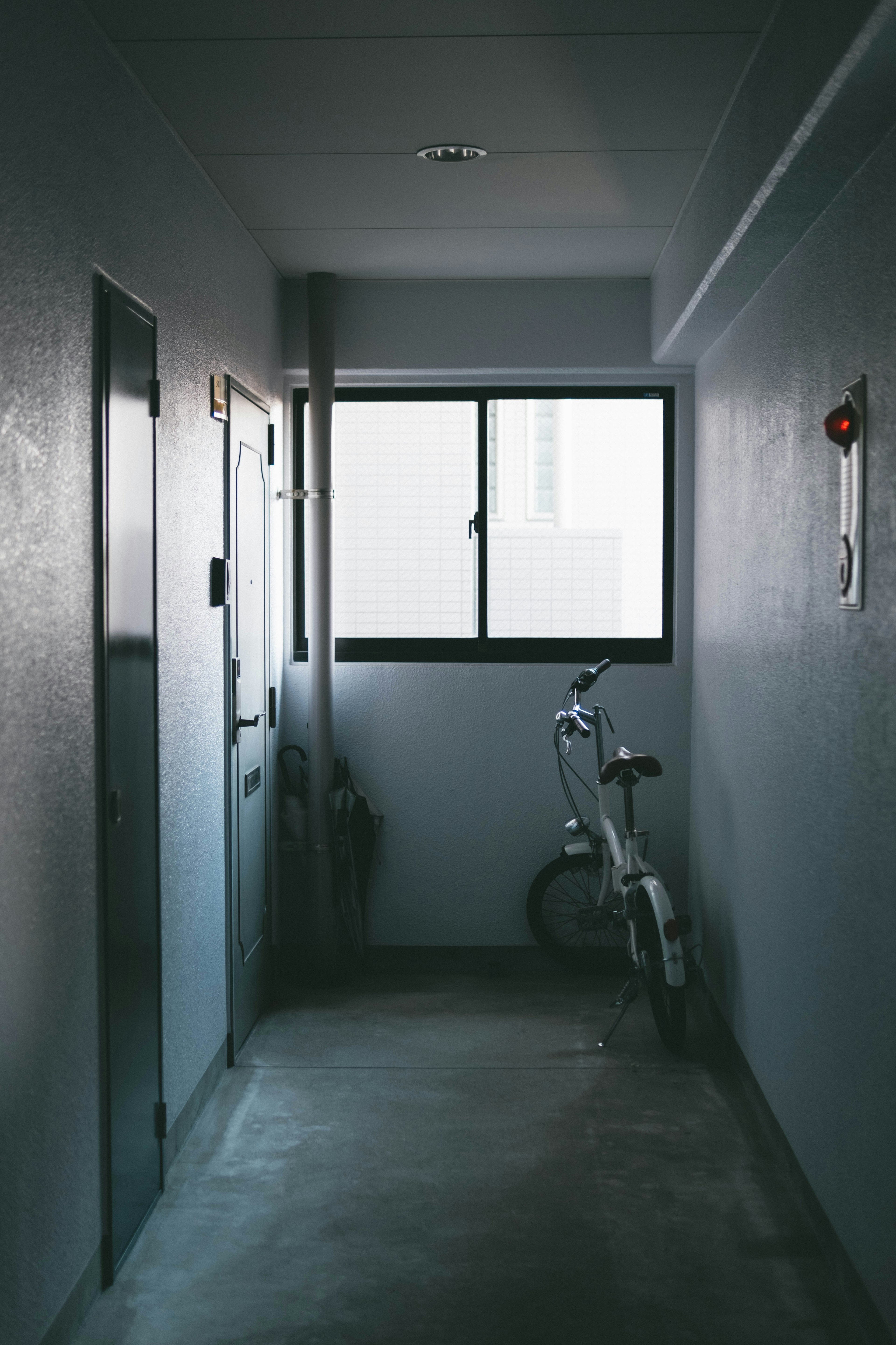 Un couloir étroit avec un vélo contre le mur et une fenêtre laissant entrer la lumière naturelle