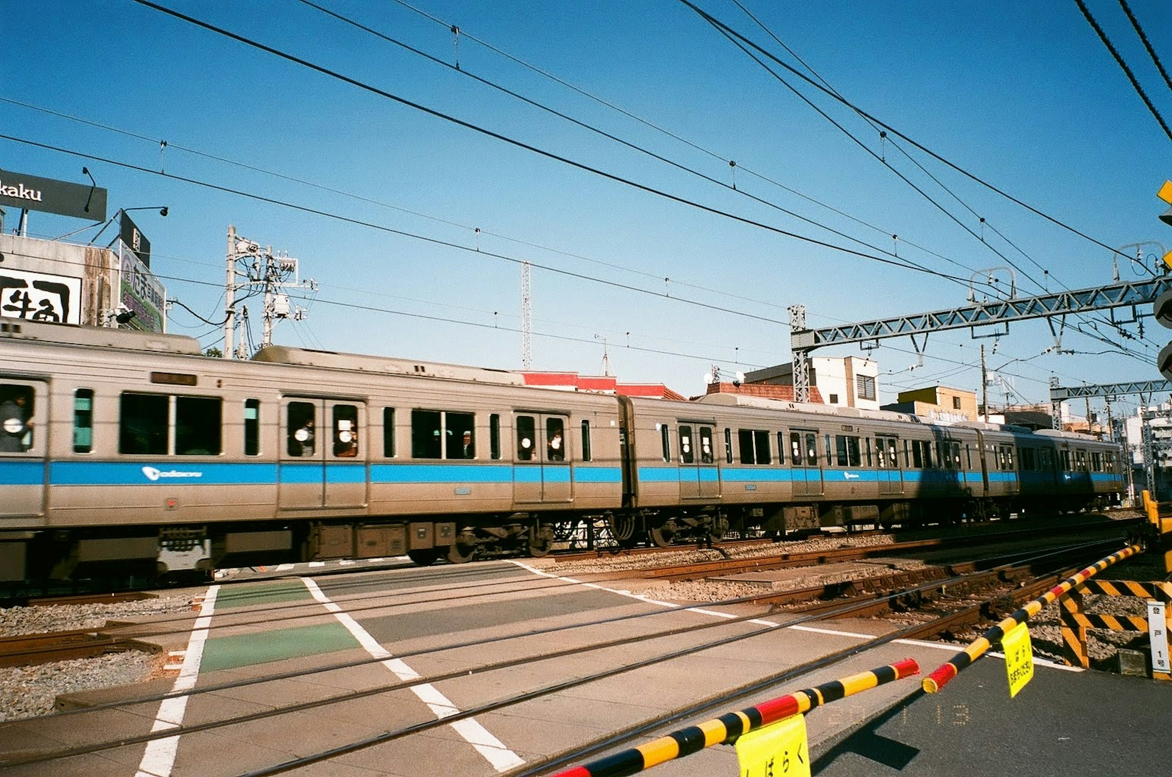 Zug, der unter einem klaren blauen Himmel durch einen Bahnübergang fährt