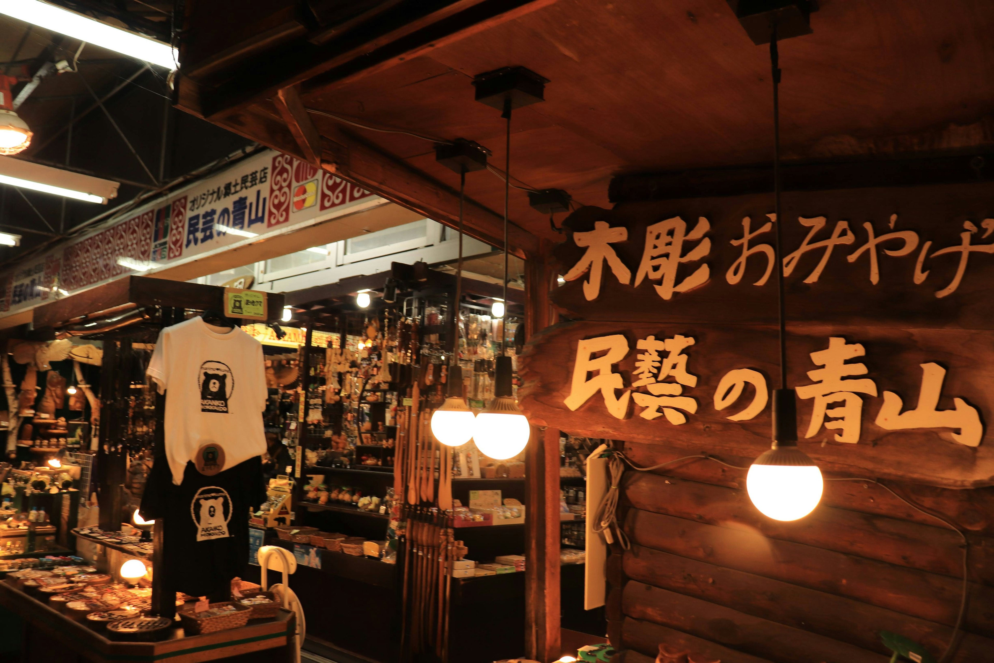 Scene of a wooden carving shop in a market with hanging lights