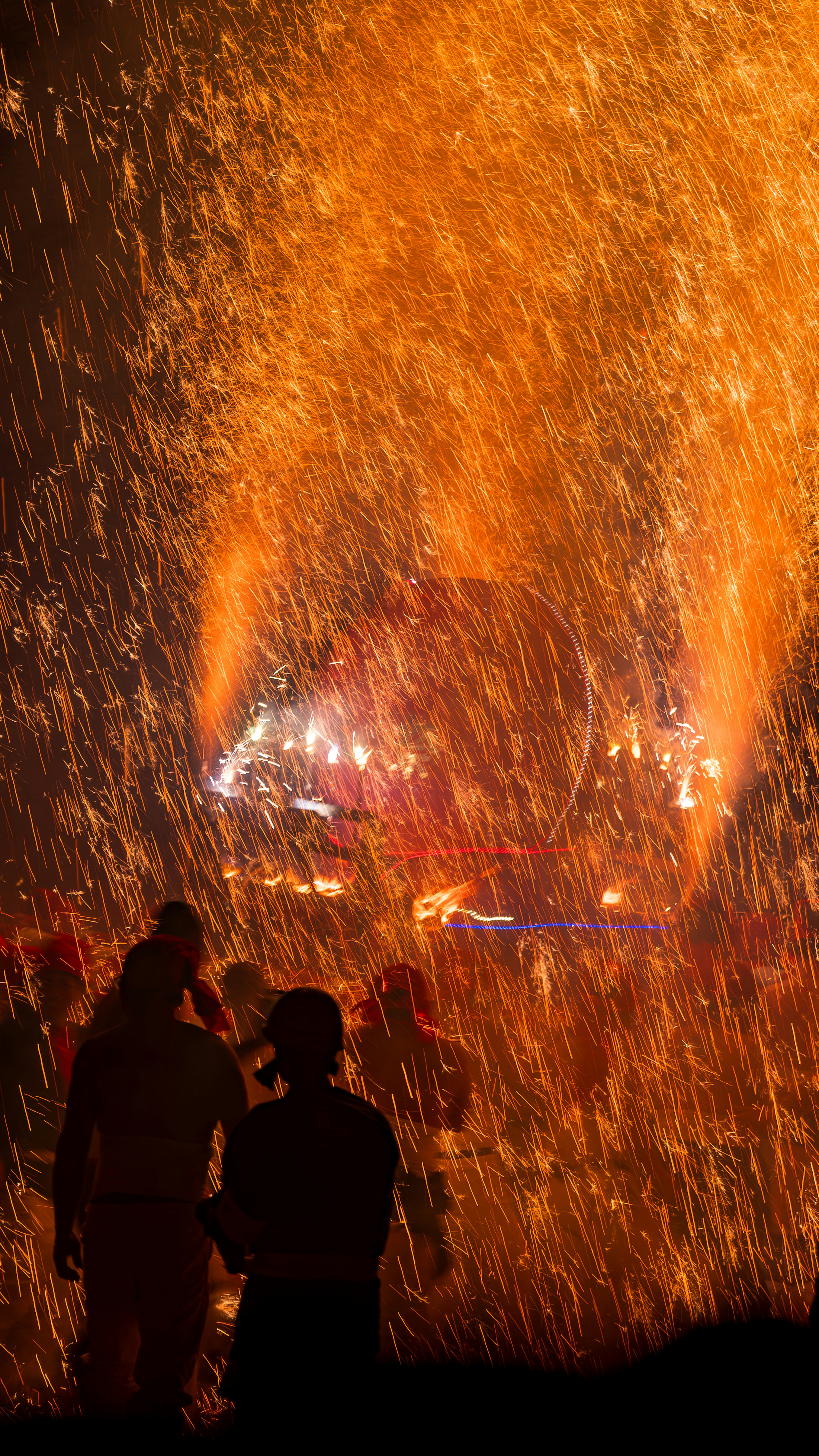 Silhouettes de deux personnes se tenant au milieu d'une pluie d'étincelles et de flammes