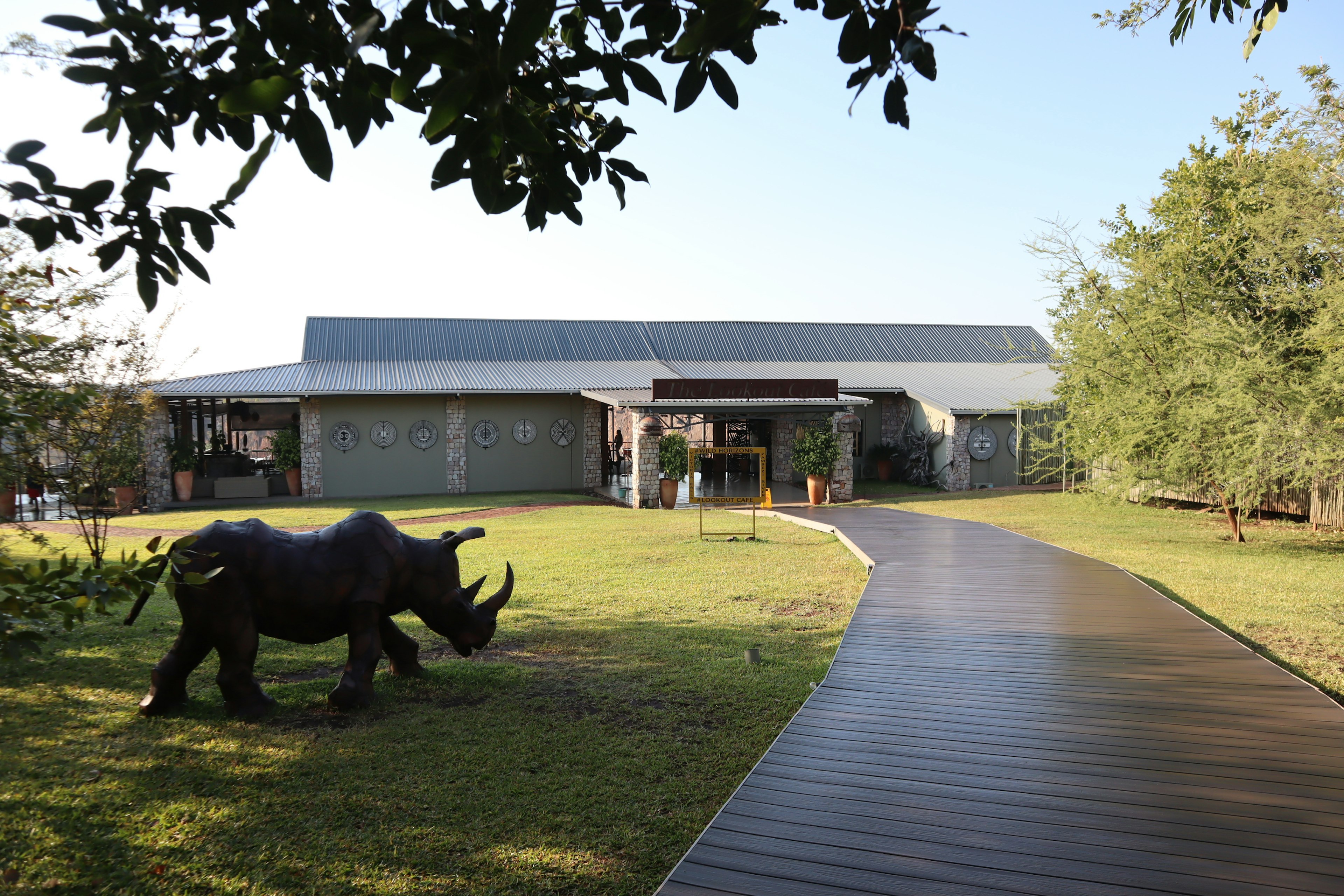 A black rhino sculpture in front of a modern building with a pathway