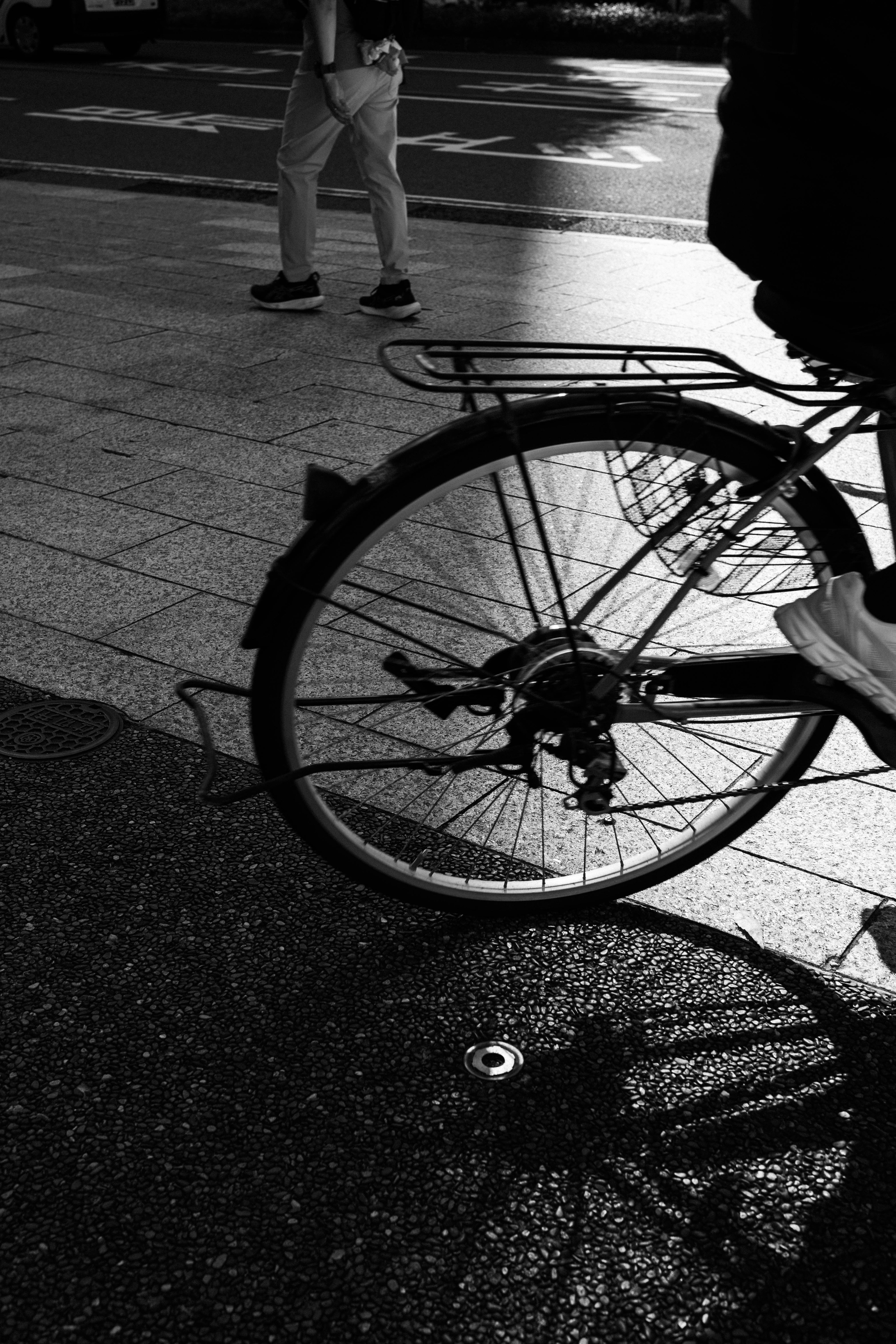 自転車の車輪と影が映るモノクロの街の風景