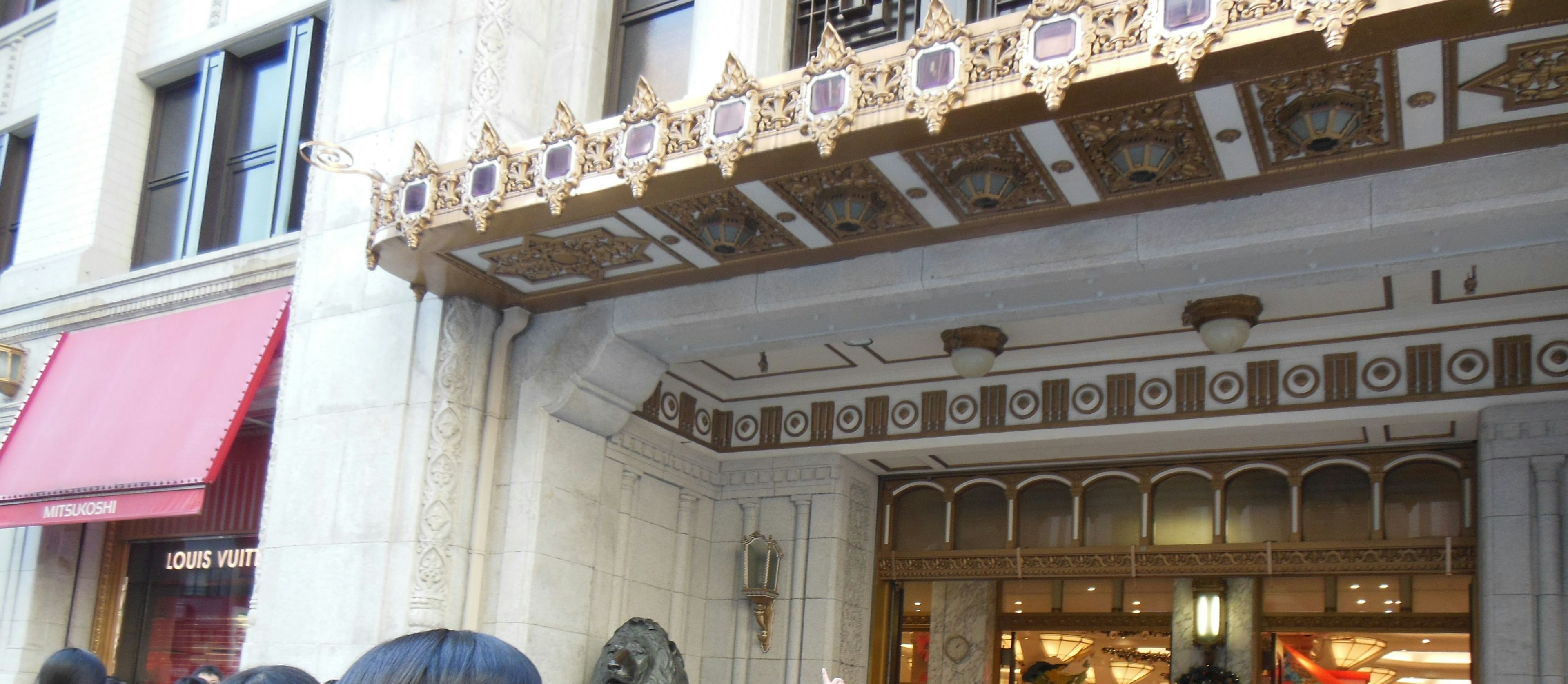 Entrance of a luxurious building with decorative signage and people gathered