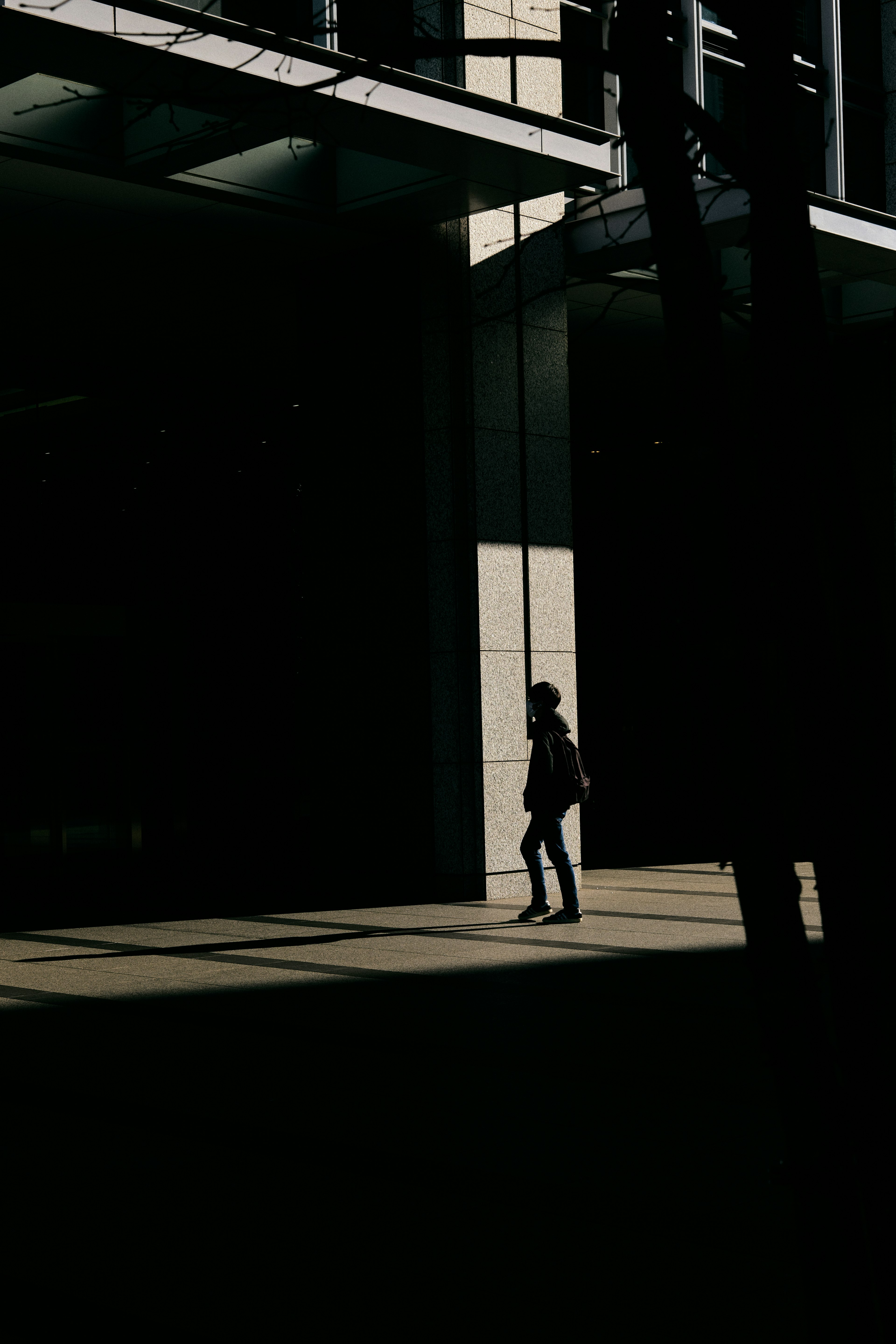 A person walking in shadows with prominent contrast against the building