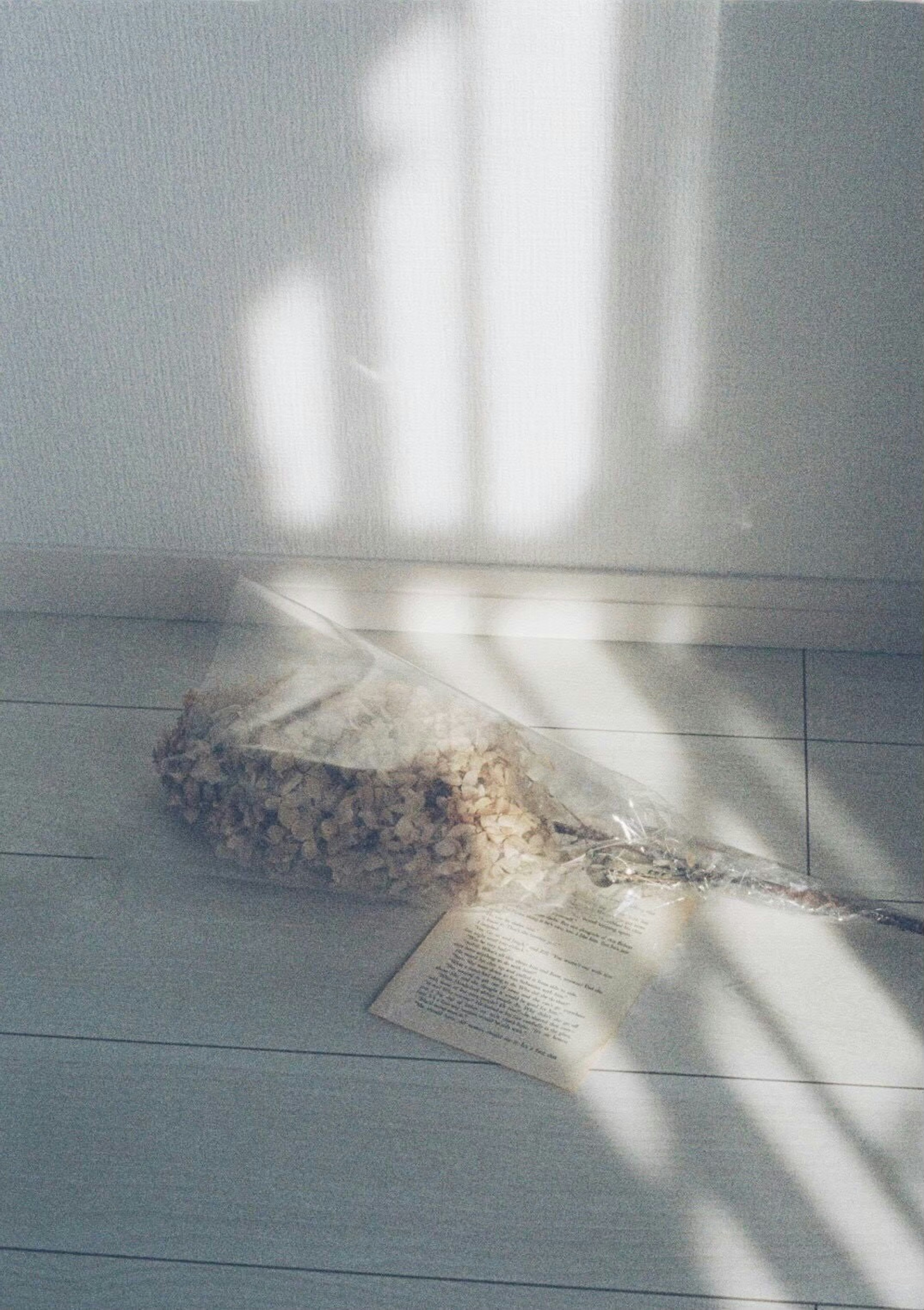 Dried flower bouquet and paper on a floor with soft light streaming in